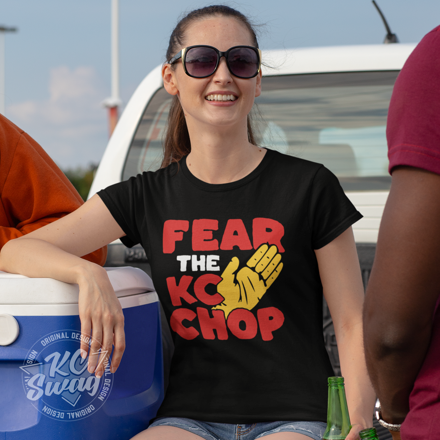 KC Swag - Kansas City Chiefs FEAR THE TOMAHAWK KC CHOP on black unisex t-shirt worn by female model sitting in the bed of a truck tailgating in a stadium parking lot
