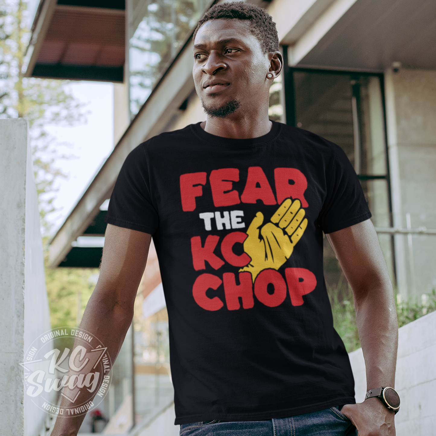 KC Swag - Kansas City Chiefs FEAR THE TOMAHAWK KC CHOP on black unisex t-shirt worn by male model leaning on railing in front of an apartment building