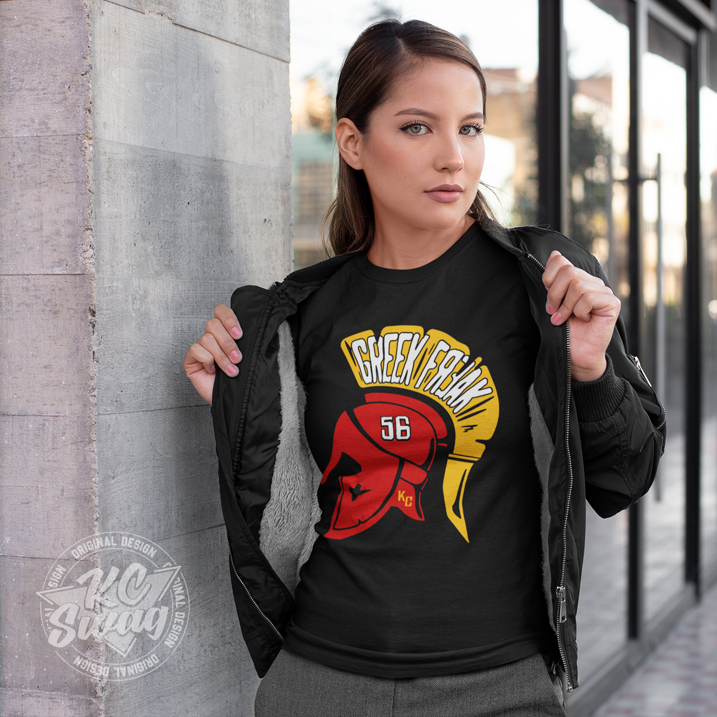 KC Swag - Kansas City Chiefs FEAR THE GREEK FREAK KARLAFTIS on black unisex t-shirt worn by female model under open jacket leaning on concrete pillar