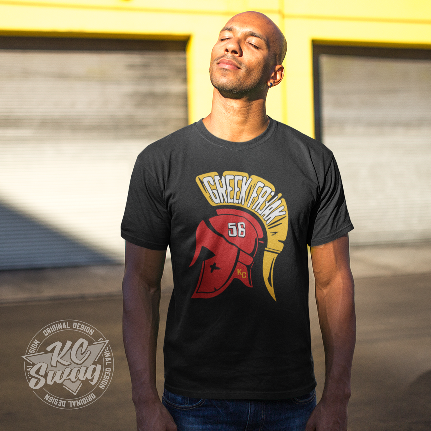 KC Swag - Kansas City Chiefs FEAR THE GREEK FREAK KARLAFTIS on black unisex t-shirt worn by male model basking in the sun in an urban alley
