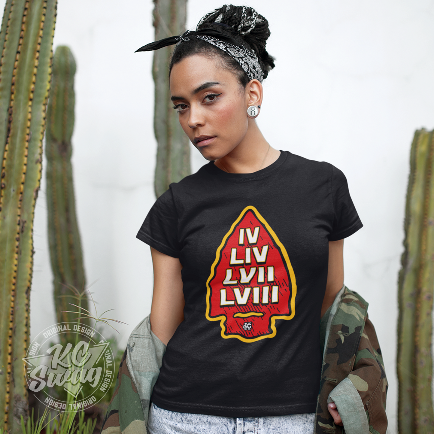 KC Swag - Kansas City Chiefs SUPER BOWL VICTORY ARROWHEAD on black unisex t-shirt worn by female model standing in front of a white wall and cacti