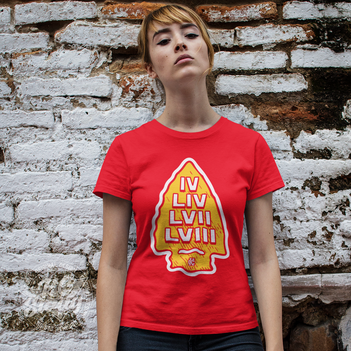 KC Swag - Kansas City Chiefs SUPER BOWL VICTORY ARROWHEAD on red unisex t-shirt worn by female model leaning against a red and white brick wall