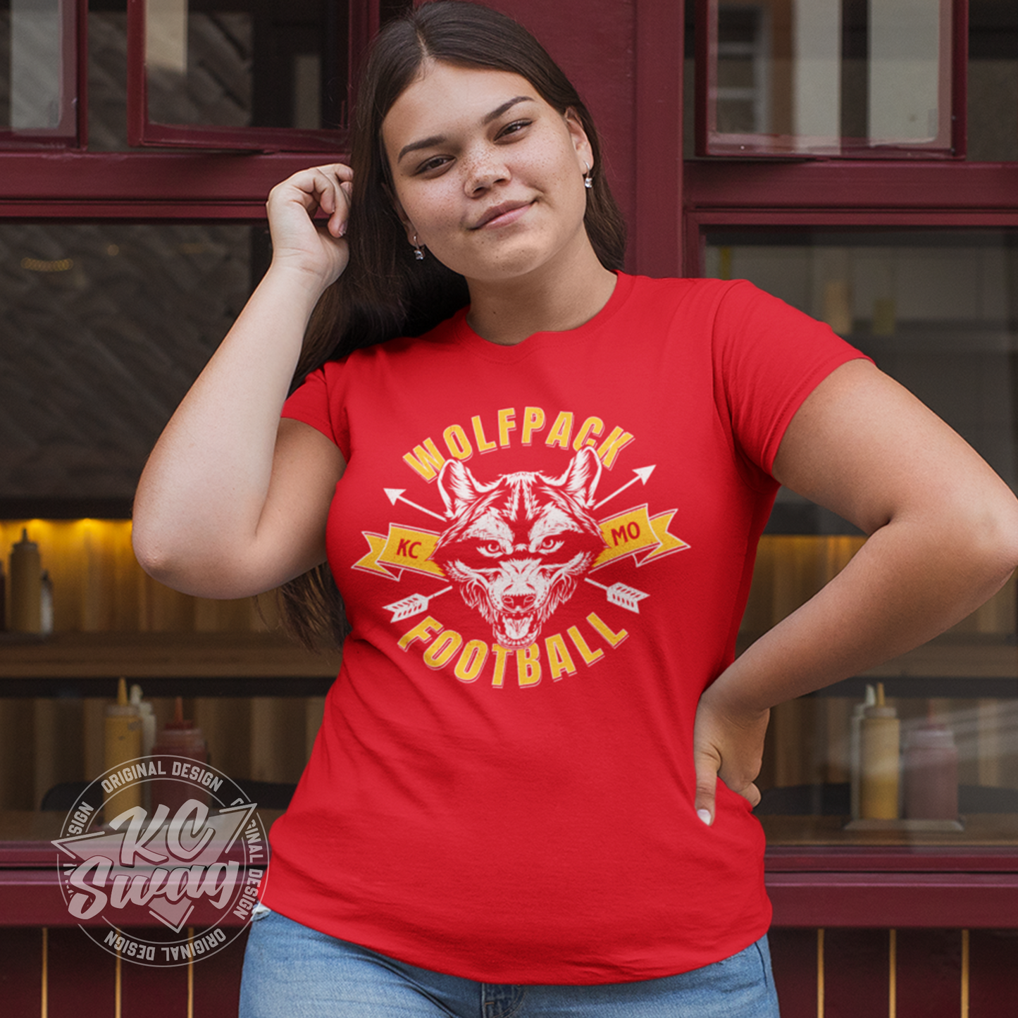 KC Swag - Kansas City Chiefs WOLFPACK FOOTBALL KCMO on red unisex t-shirt worn by female model standing outside of restaurant windows