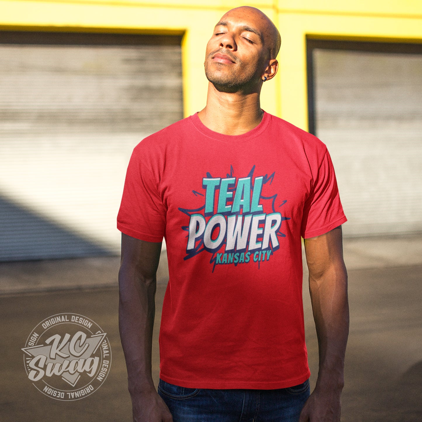 KC Swag - Kansas City Current, Teal Power KC design on red unisex t-shirt worn by male model basking in the sunlight while standing in an urban alley