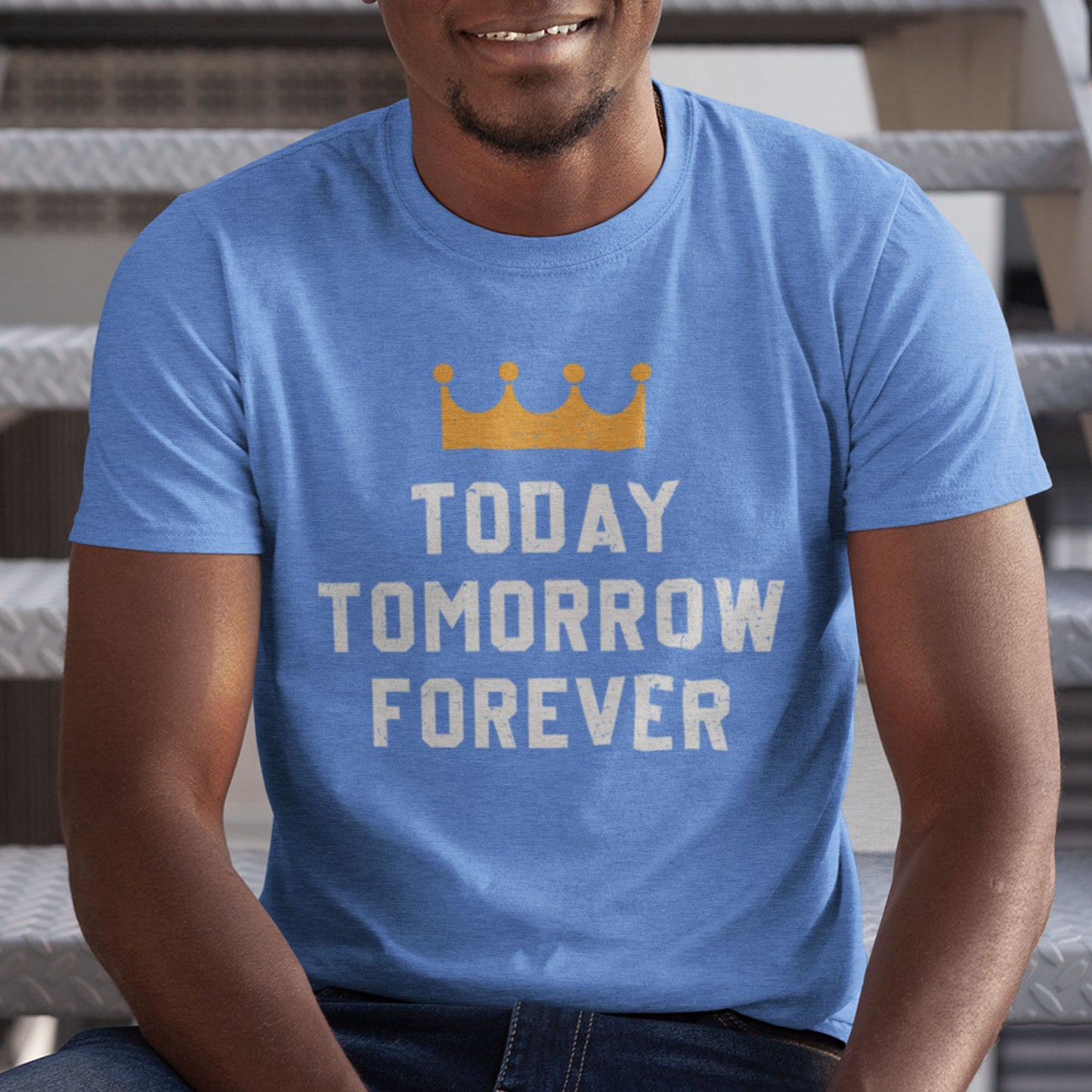 kc swag, kansas city royals, heather columbia blue unisex t-shirt featuring a gold crown above white text that says "Today, Tomorrow, Forever" with a distressed, worn-out look, worn by smiling male model sitting on a metal staircase in a parking garage