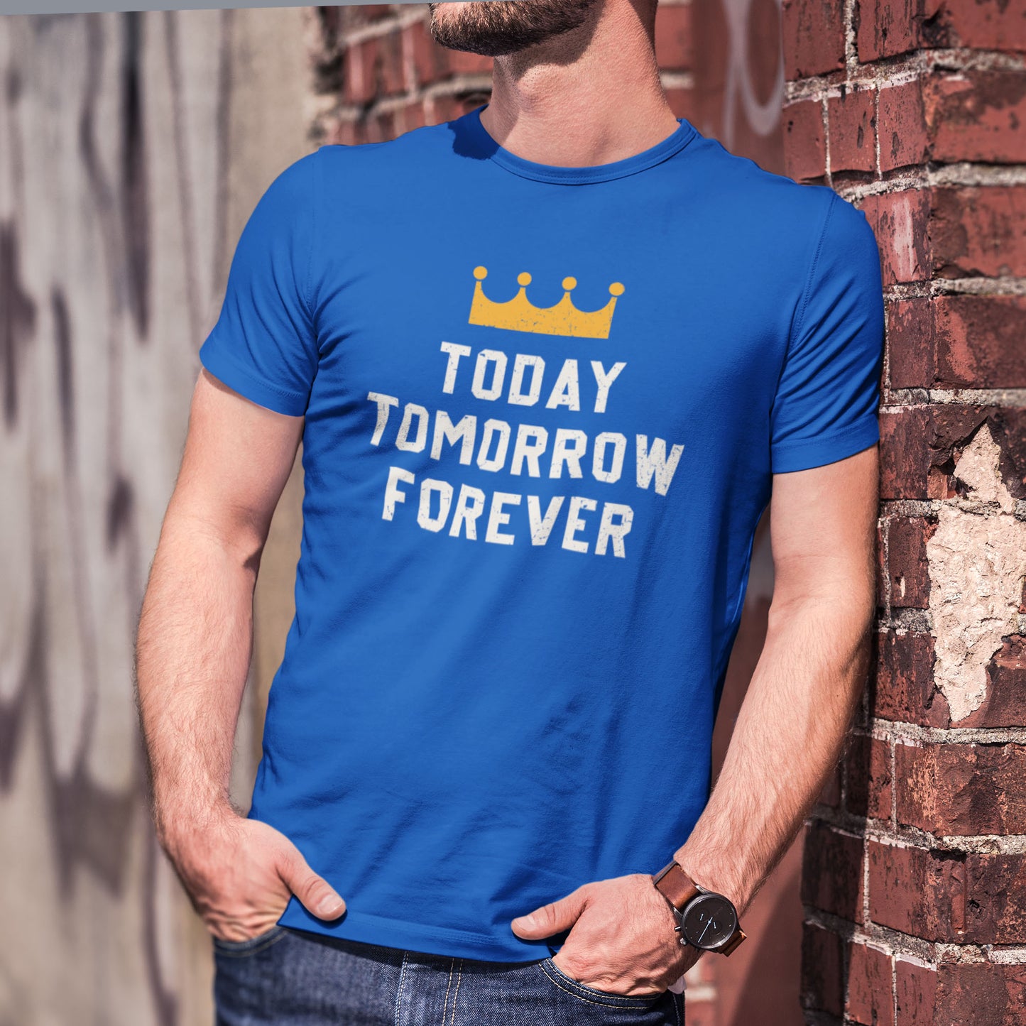 kc swag, kansas city royals, royal blue unisex t-shirt featuring a gold crown above white text that says "Today, Tomorrow, Forever" with a distressed, worn-out look, worn by a bearded male model leaning against a brick wall in an urban setting