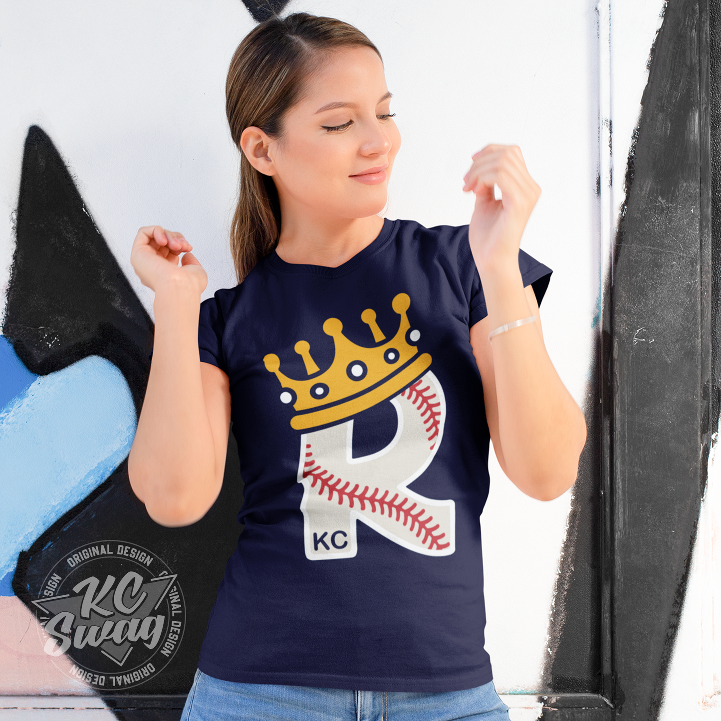 KC Swag - Kansas City Royals CROWN R-BALL KC on team navy blue unisex t-shirt worn by female model dancing in front of a graffiti wall in an urban setting