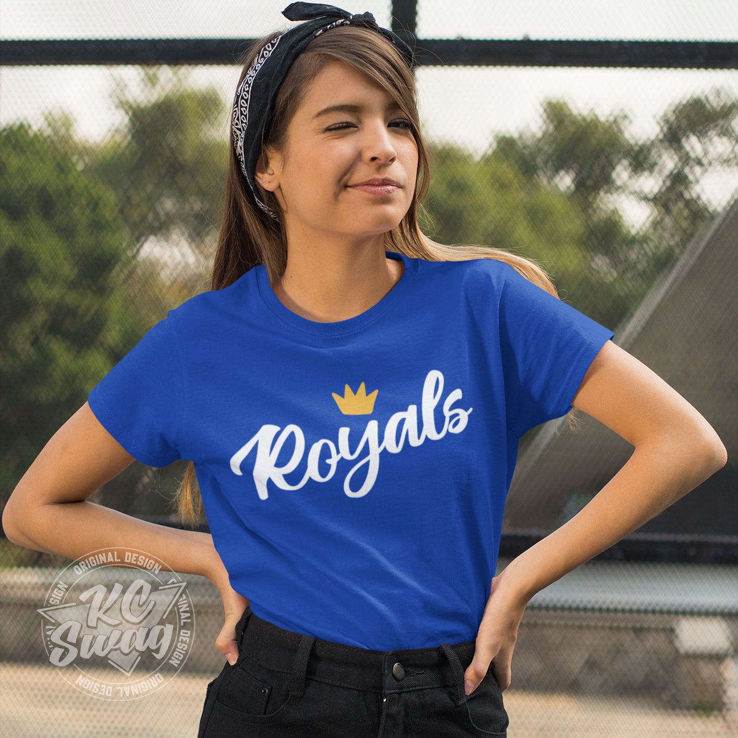 KC Swag - Kansas City Royals, FRoyals Flower Crown design on royal blue unisex t-shirt worn by female model with her hands on her hips and wearing a bandana in front of a chainlink fence in a park
