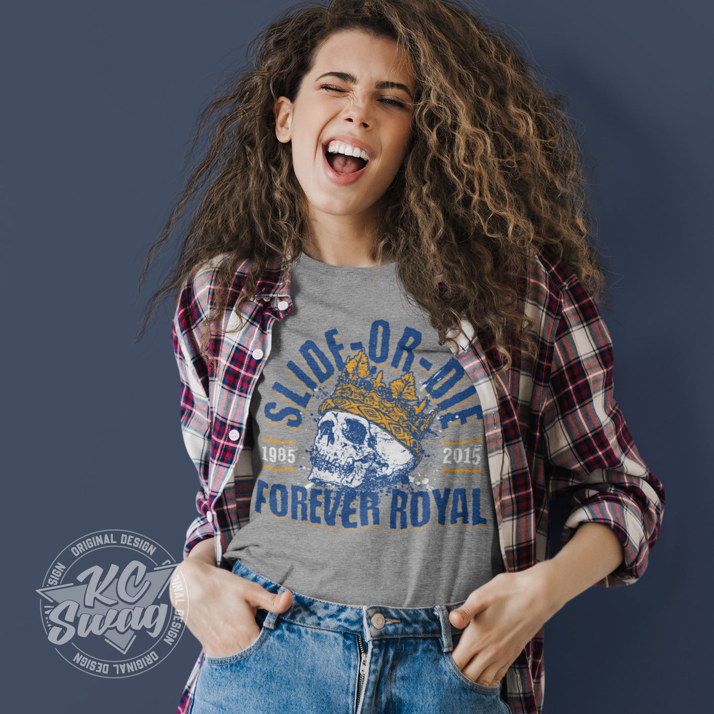 KC Swag - Kansas City Royals, Slide Or Die Forever Royal design on athletic heather grey unisex t-shirt worn by winking female model under open plaid shirt standing in front of a blue studio wall