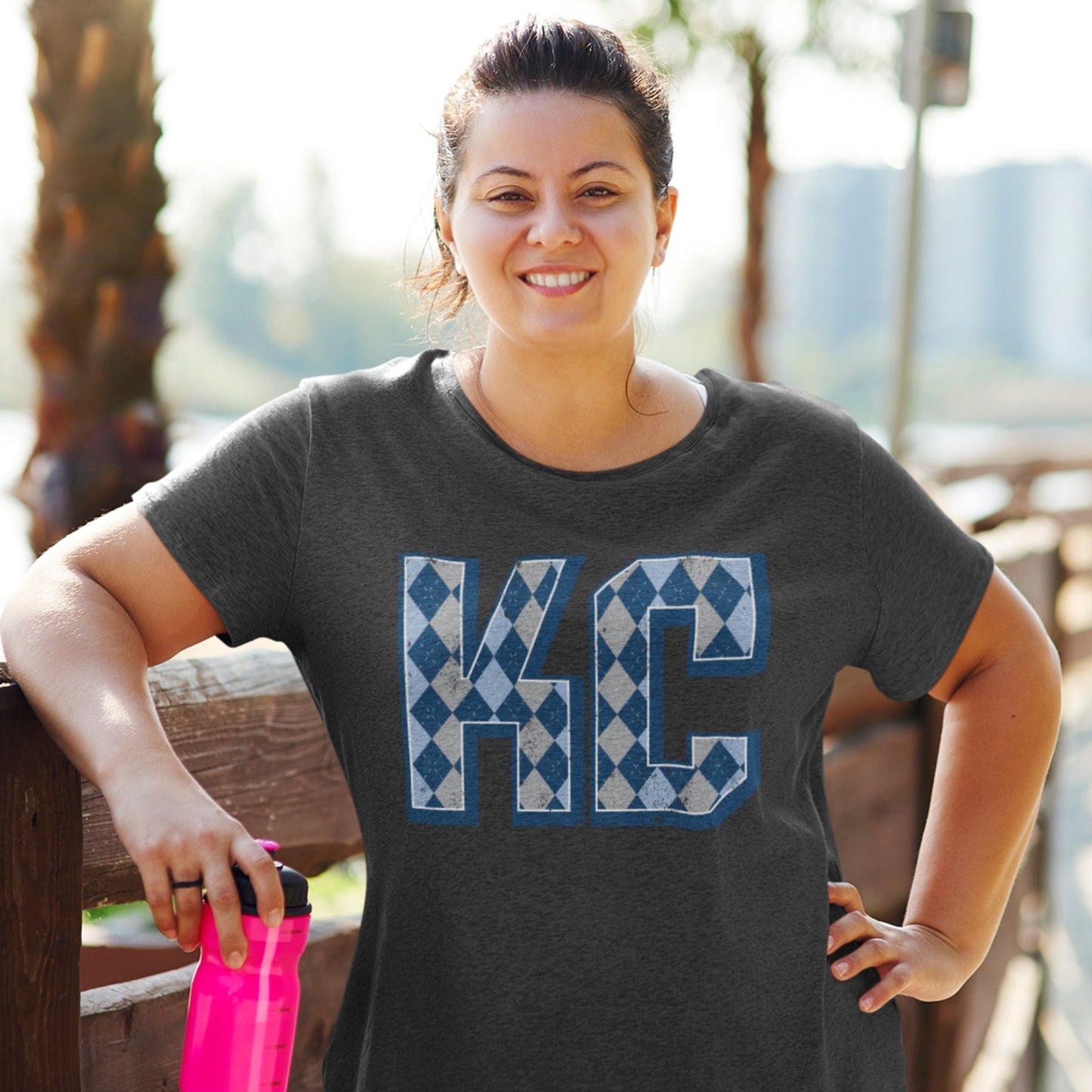 KC Swag Sporting Kansas City powder blue/navy/grey ARGYLE PATTERN KC on dark heather grey t-shirt worn by female model in sunny outdoor setting