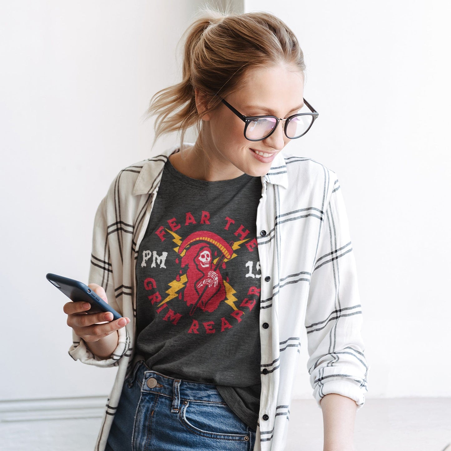 KC Swag Kansas City Chiefs GRIM REAPER PM15 on dark heather grey t-shirt worn by female model in bright room holding phone