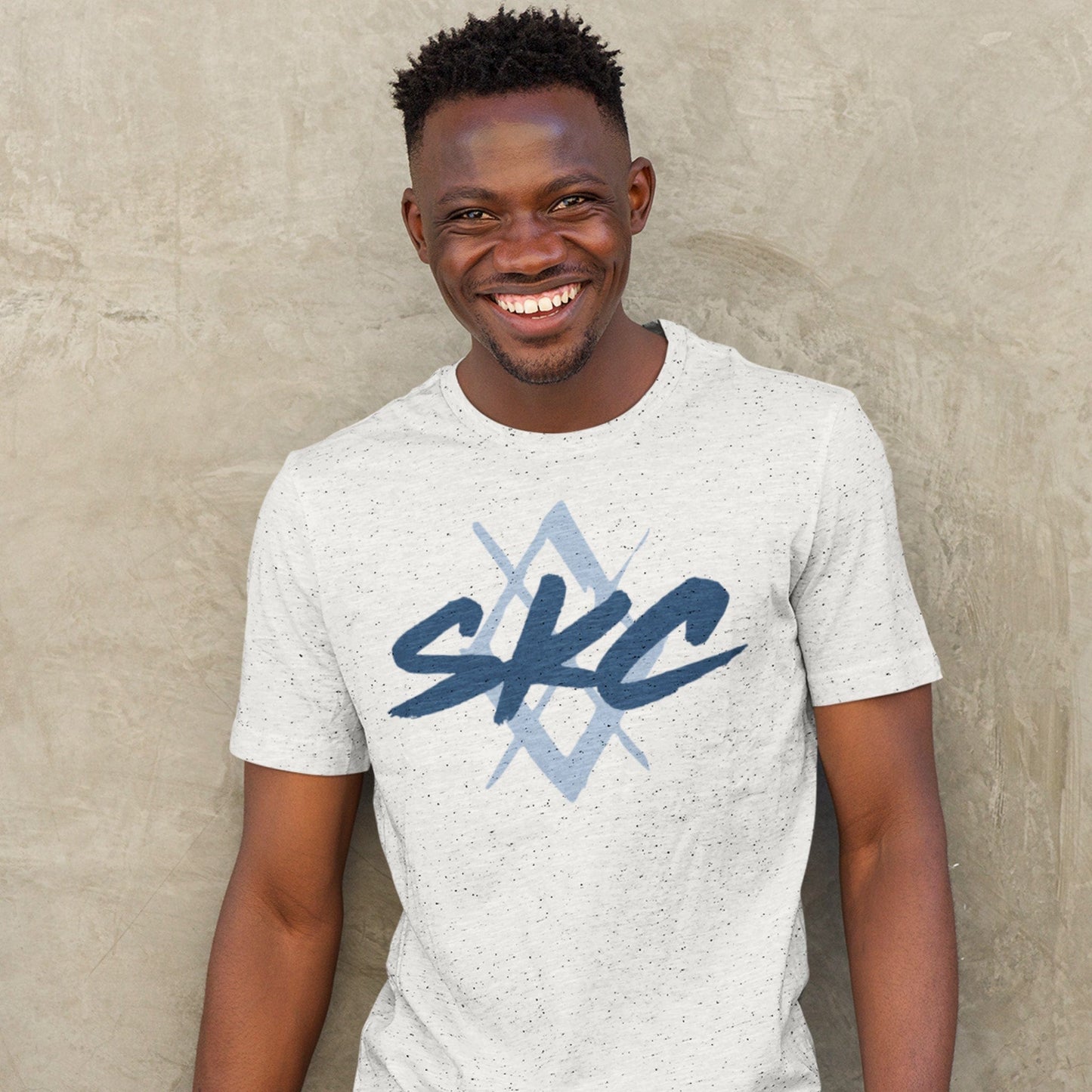 KC Swag Sporting Kansas City PAINTED SKC DIAMOND on heather ash unisex t-shirt worn by male model standing in front of stone wall