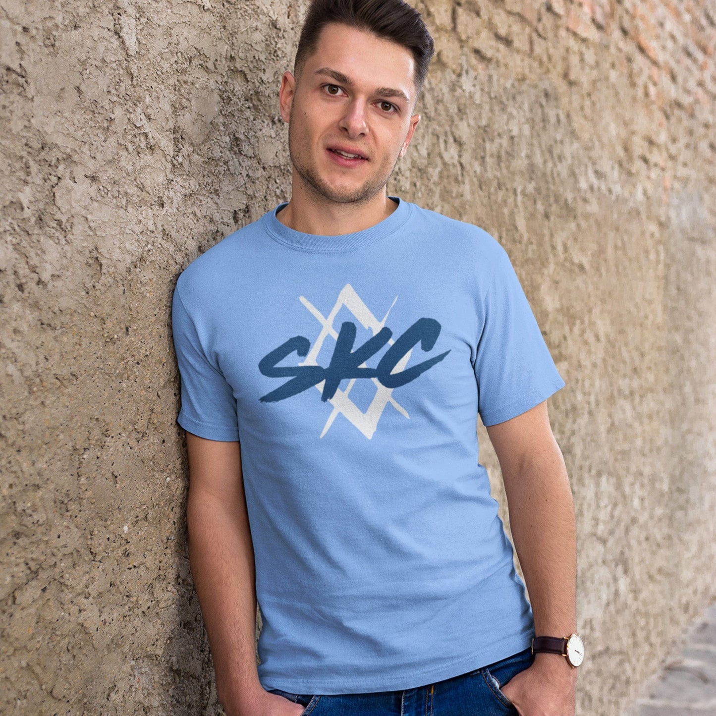 KC Swag Sporting Kansas City PAINTED SKC DIAMOND on baby blue unisex t-shirt worn by male model leaning against concrete wall