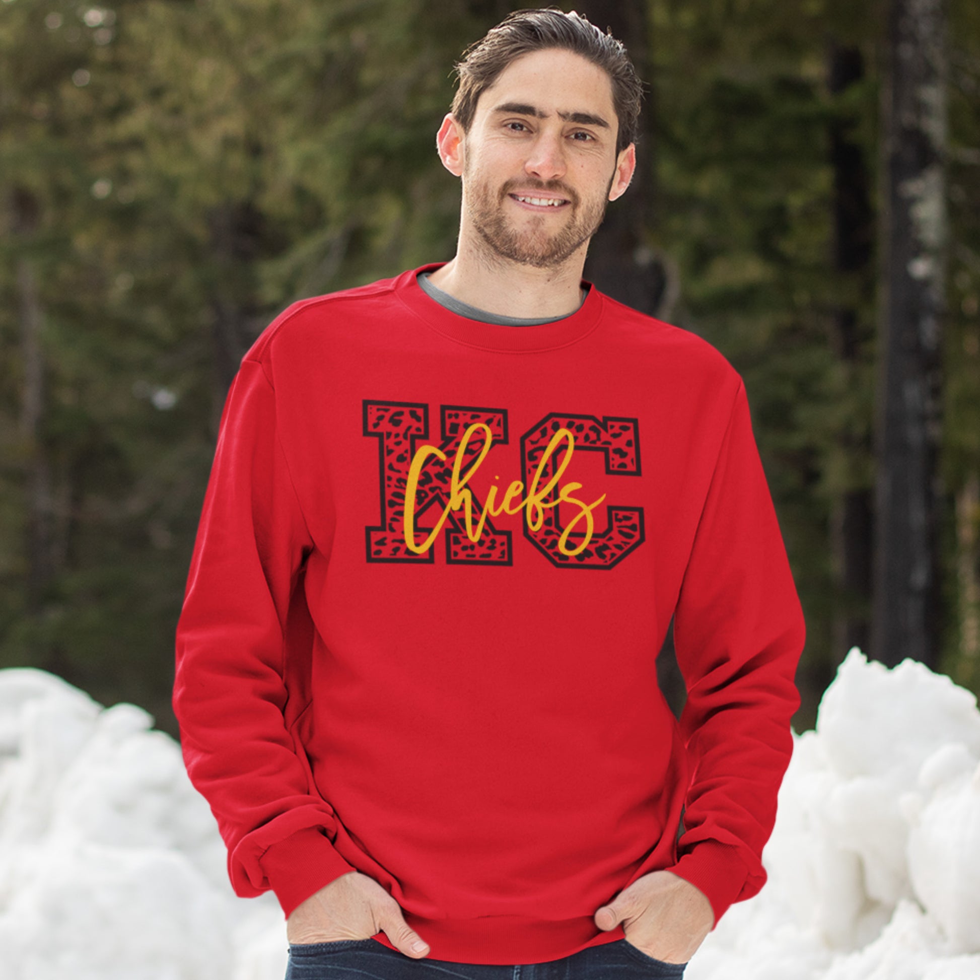 KC Swag Kansas City Chiefs Black & Gold Cheetah KC on a Red Crewneck Sweatshirt worn by a male model with is hands in his pockets standing in a snow covered forrest
