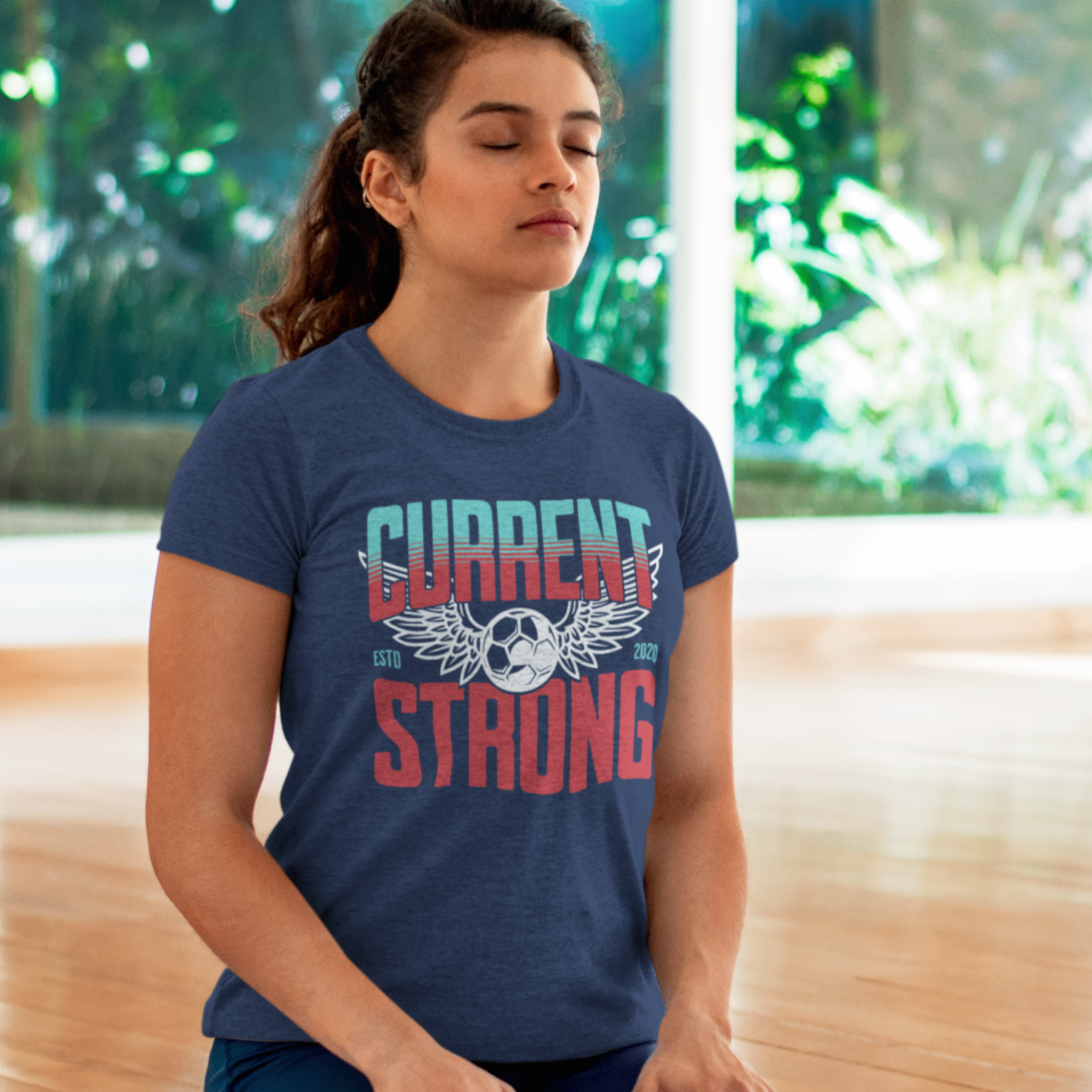 KC Swag Kansas City Current CURRENT STRONG on heather navy unisex t-shirt worn by female model on her knees meditating in a yoga studio