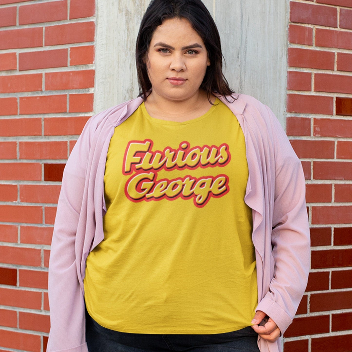 KC Swag | Kansas City Chiefs red & white FURIOUS GEORGE on maize yellow unisex t-shirt worn by plus-sized female model leaning on corner of brick building