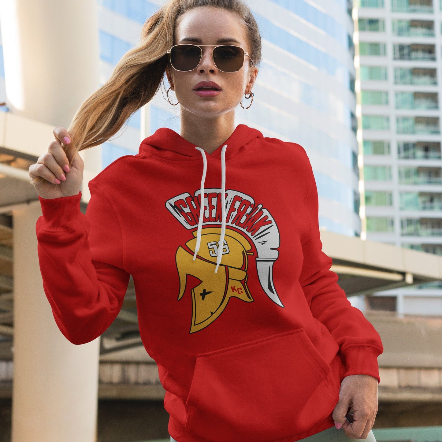 KC Swag | Kansas City Chiefs white/gold GREAT FREAK 56 on red sponge-fleece pullover hoodie worn by female model standing in front of a downtown builing