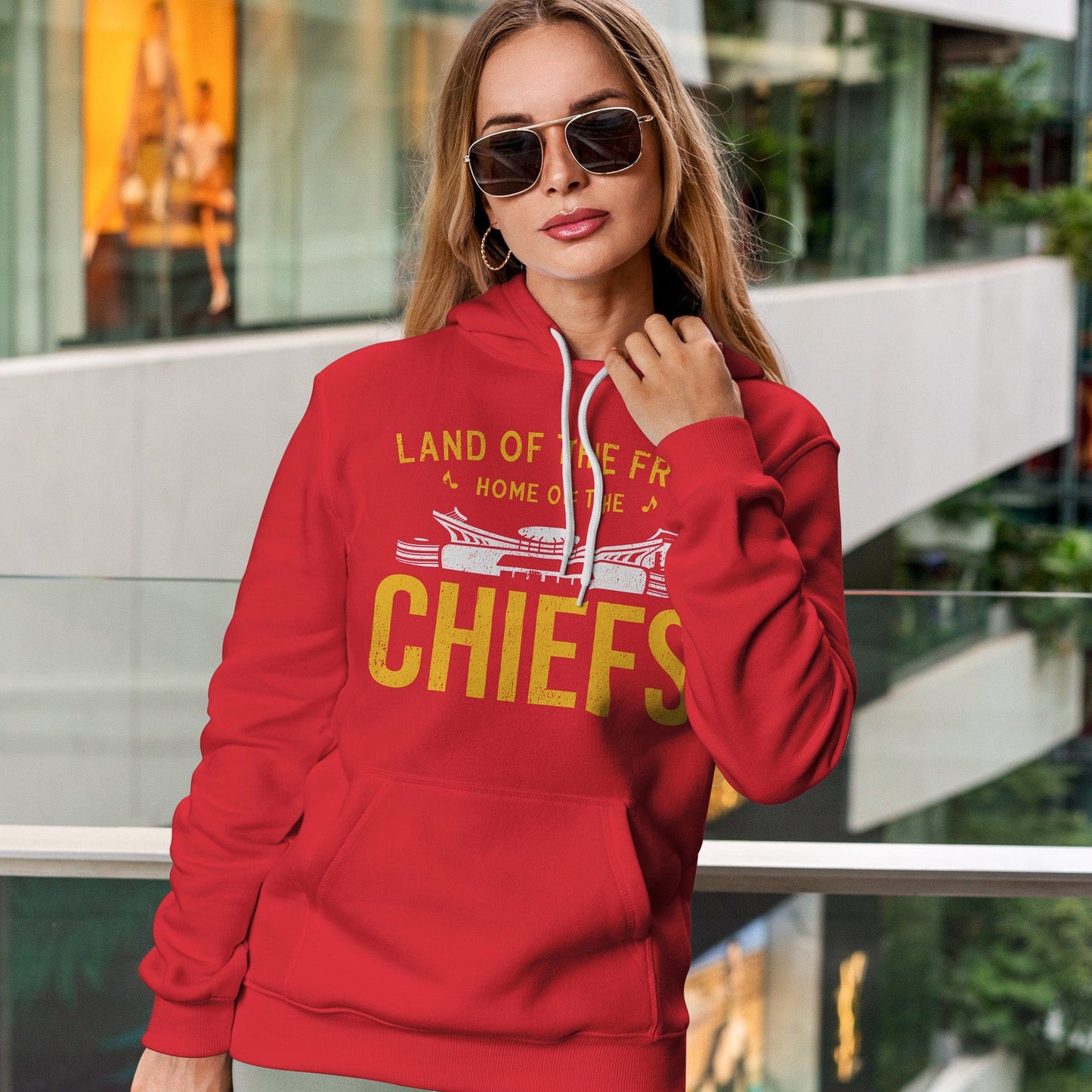 KC Swag | Kansas City Chiefs white/gold HOME OF THE CHIEFS on red sponge-fleece pullover hoodie worn by female model leaning on railing in shopping mall