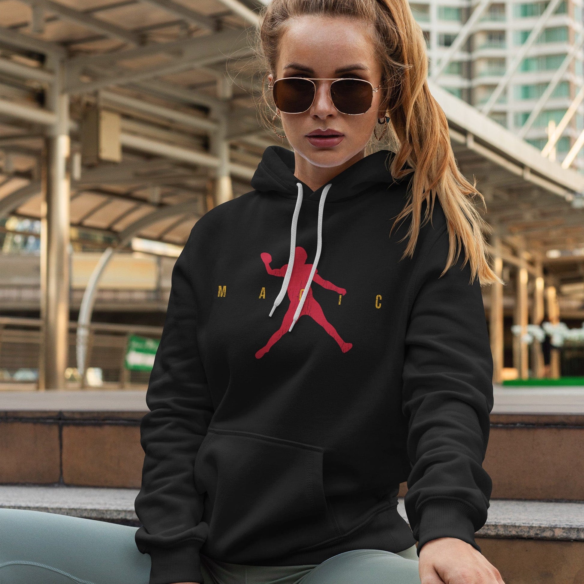 KC Swag | Kansas City Chiefs red/gold MAGIC AIR MAHOMIE on black sponge-fleece pullover hoodie worn by female model sitting outside of a downtown building