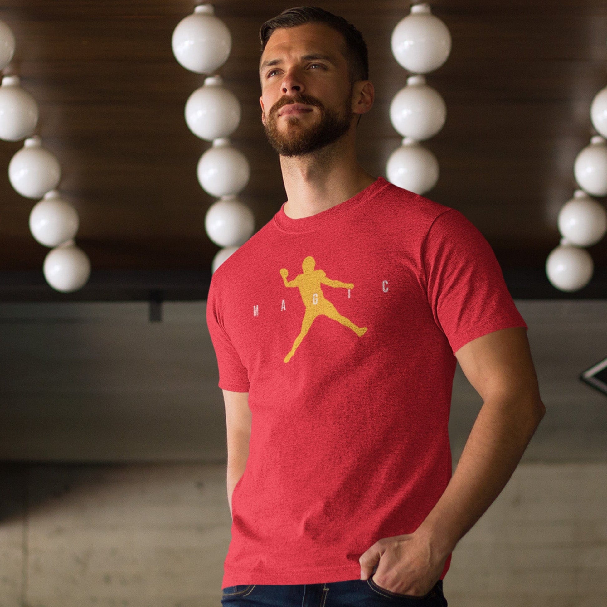 KC Swag | Kansas City Chiefs white & gold MAGIC AIR MAHOMIE on a heather red unisex t-shirt worn by a stoic male model standing under a ceiling of white globes