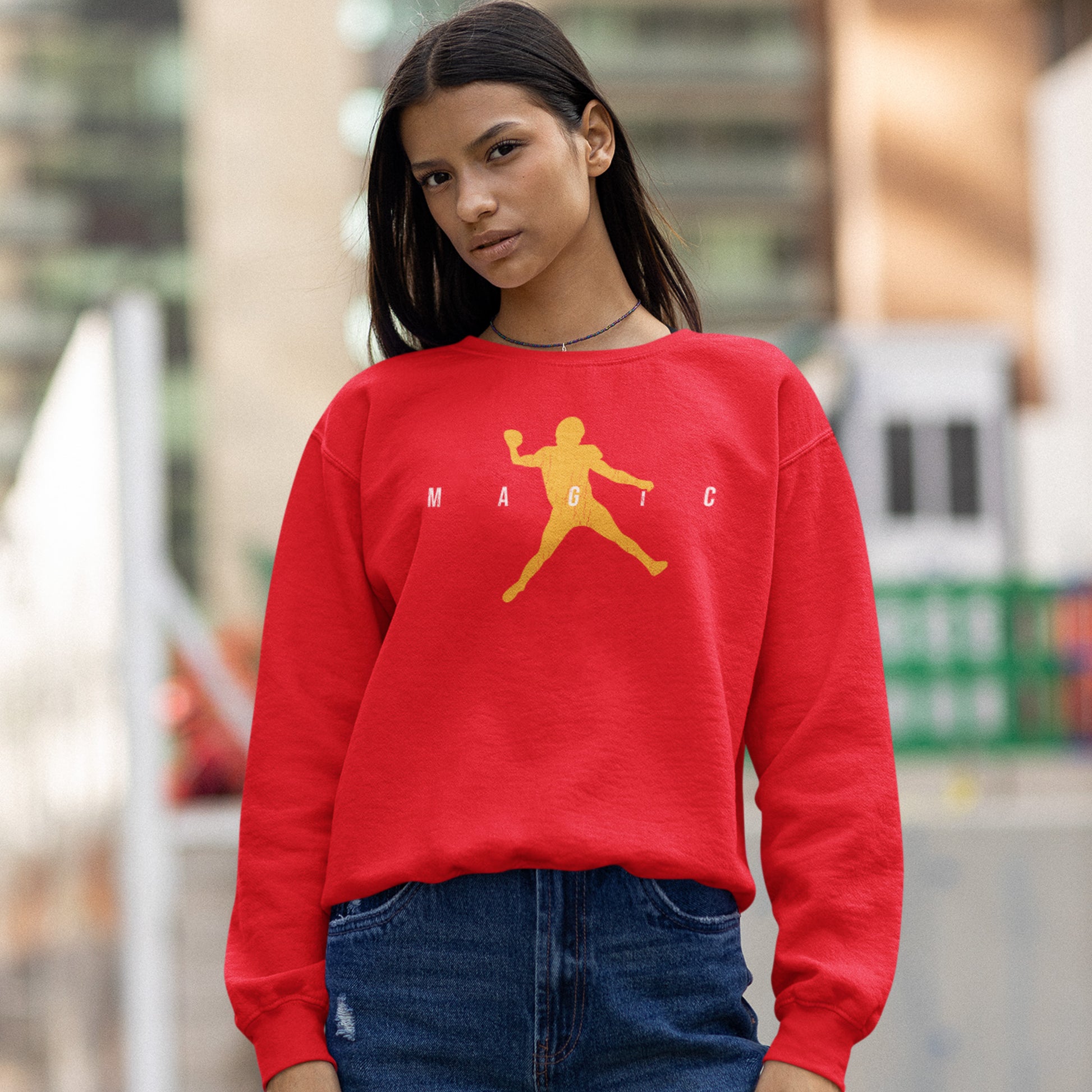 KC Swag Kansas City Chiefs Distressed White & Gold Magic Air Mahomie on a Red Crewneck Sweatshirt worn by a female model wearing jeans standing in a downtown plaza
