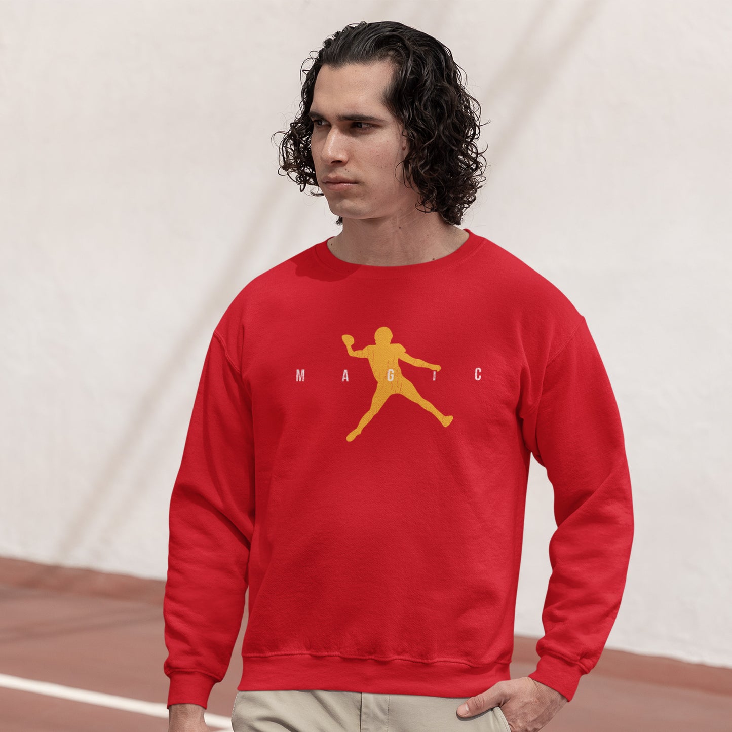 KC Swag Kansas City Chiefs Distressed White & Gold Magic Air Mahomie on a Red Crewneck Sweatshirt worn by a long-haired male model walking through an outdoor basketball court