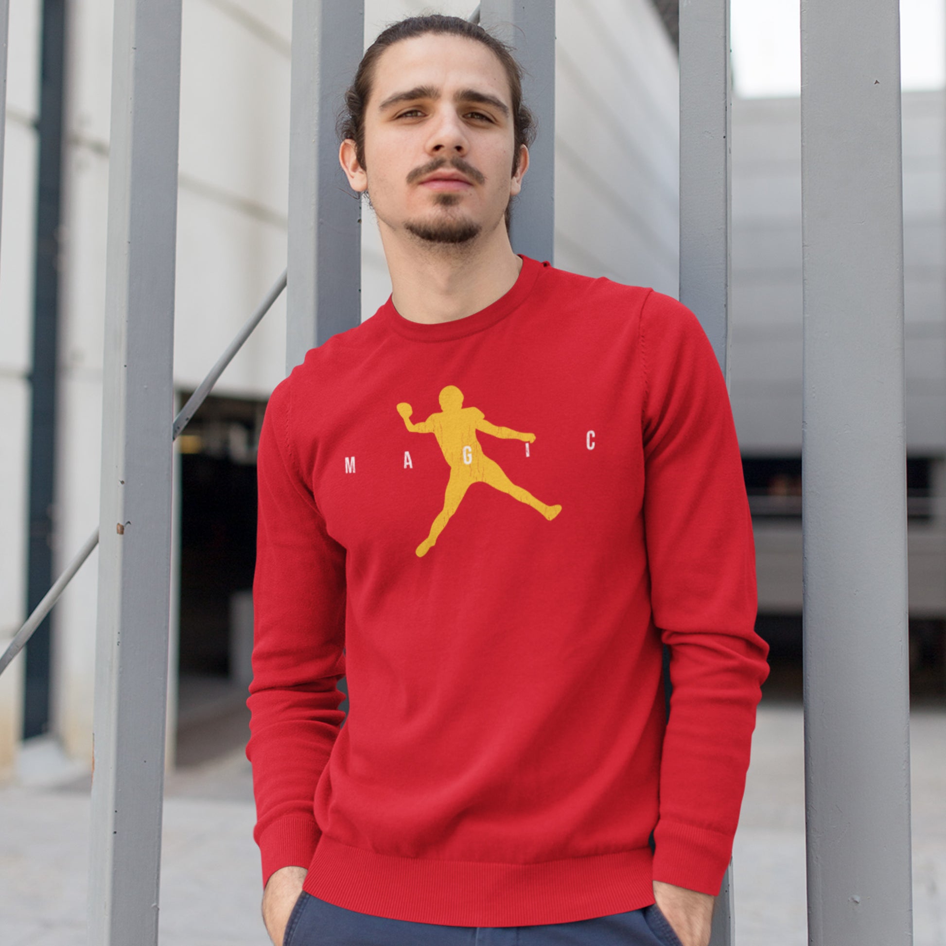 KC Swag Kansas City Chiefs Distressed White & Gold Magic Air Mahomie on a Red Crewneck Sweatshirt worn by male model with a goatee leaning against a large metal gate