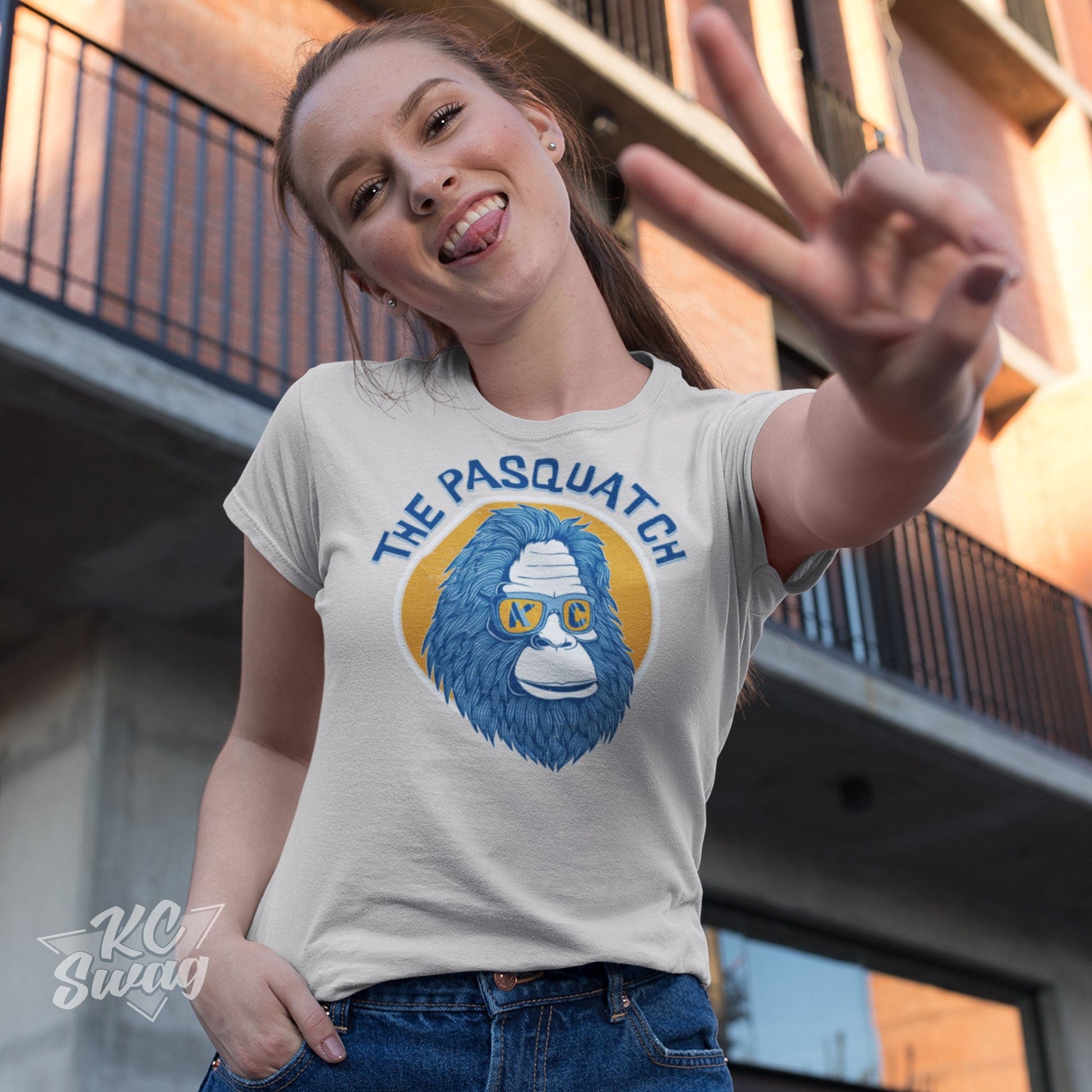 KC Swag Kansas City Royals KC PASQUATCH on natural unisex t-shirt worn by female model giving the 'peace-sign' towards the camera