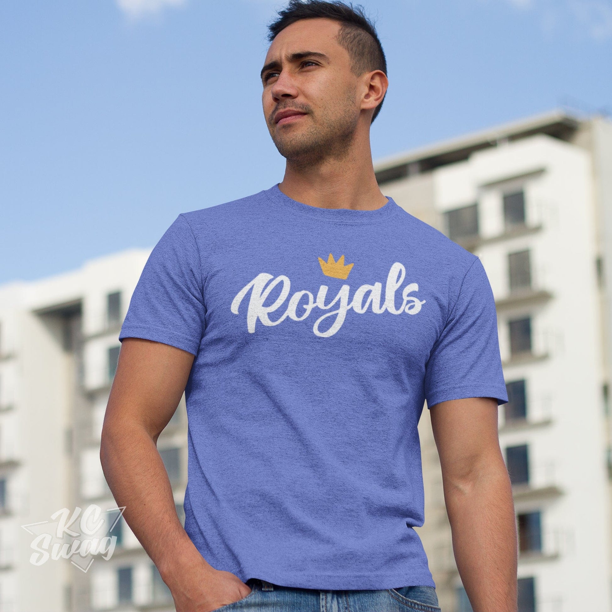 KC Swag Kansas City Royals ROYALS CROWN on heather Columbia blue unisex t-shirt worn by male model standing in front of apartment building