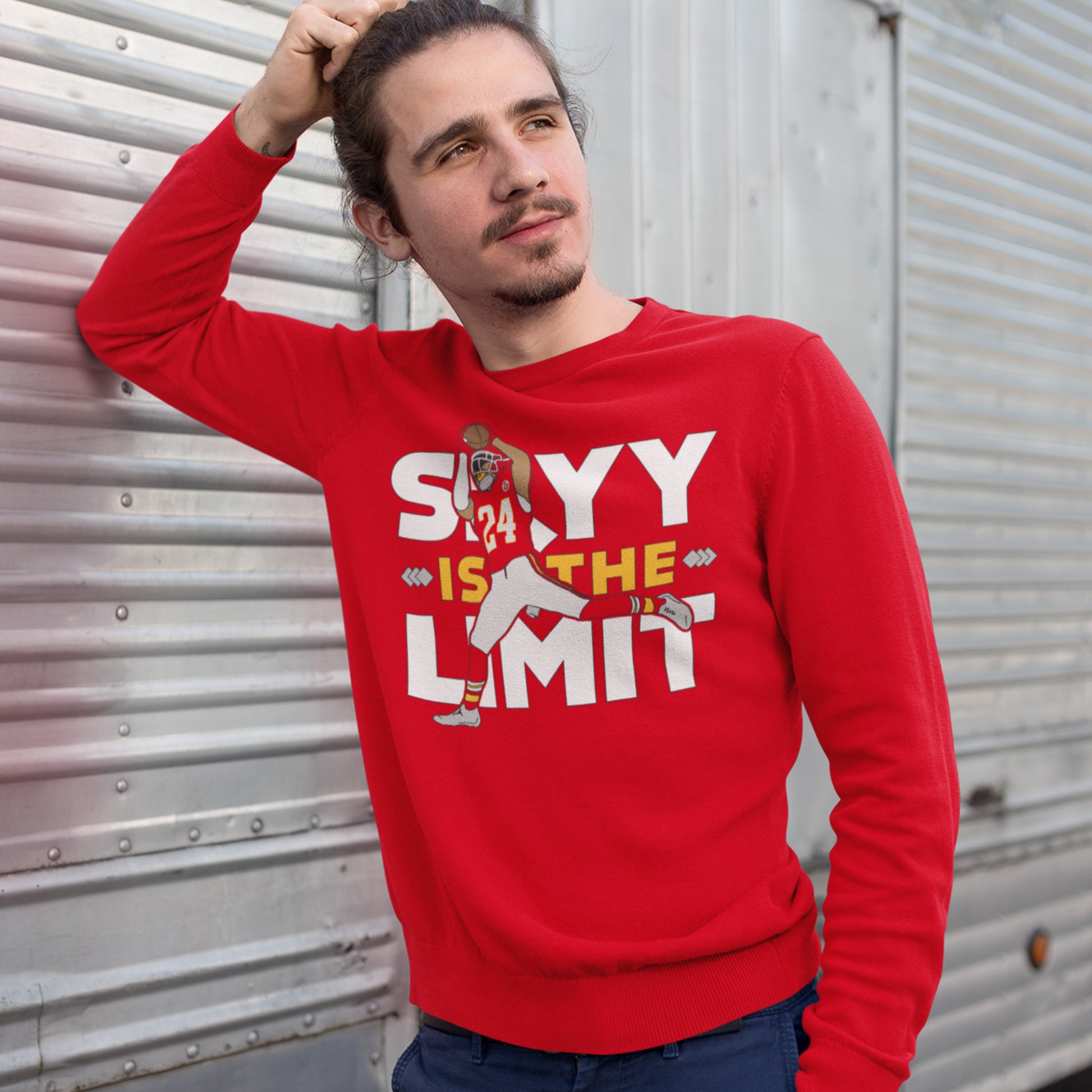 KC Swag Kansas City Chiefs White & Gold Skyy Is The Limit (with football player) on a Red Crewneck Sweatshirt worn by a male model with a goatee leaning on a metal garage door