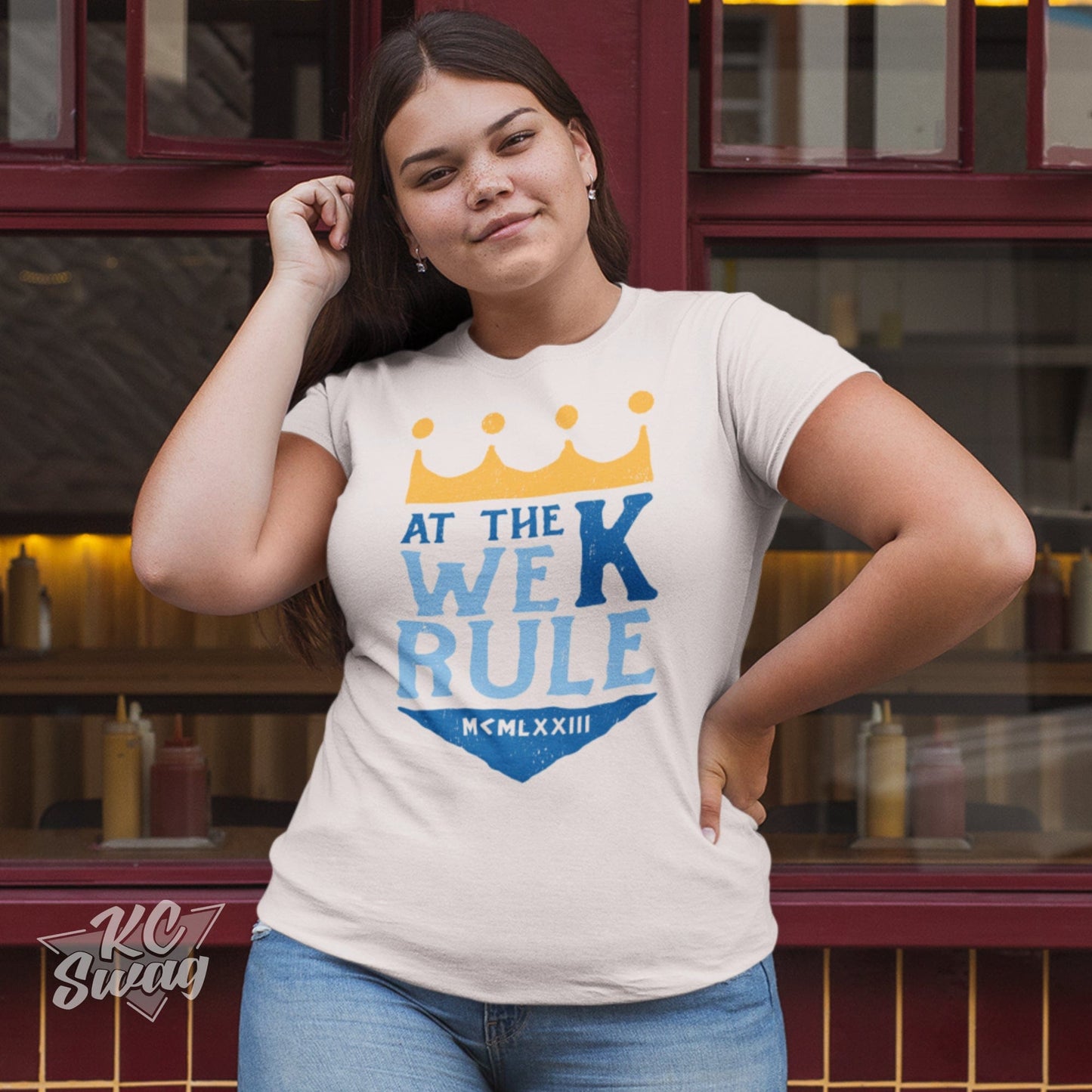 KC Swag Kansas City Royals AT THE K WE RULE on natural unisex t-shirt worn by female model standing outside of restaurant windows