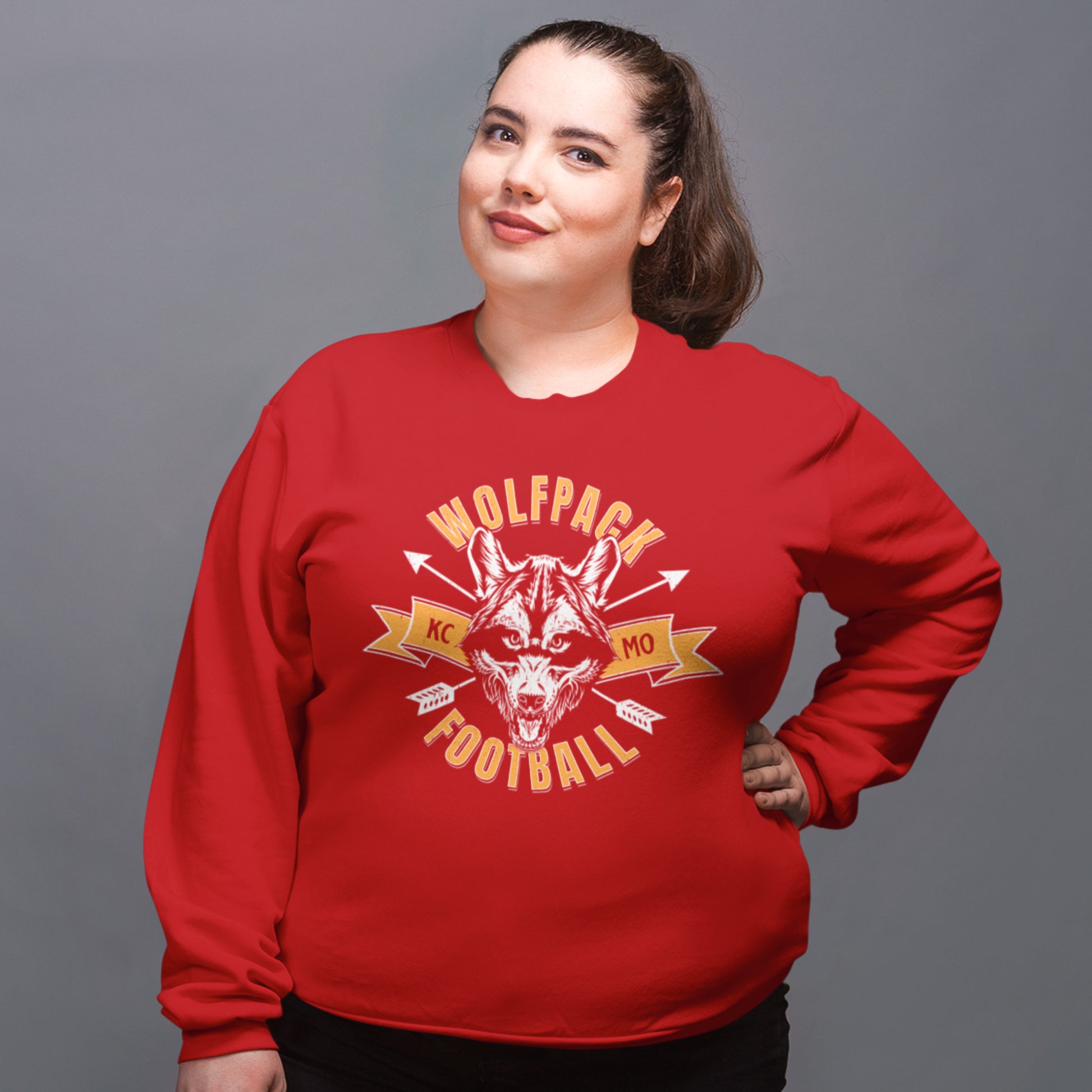 KC Swag Kansas City Chiefs Distressed White & Gold Wolfpack Football on a Red Crewneck Sweatshirt worn by a plus-size female model standing in front of a gray studio wall