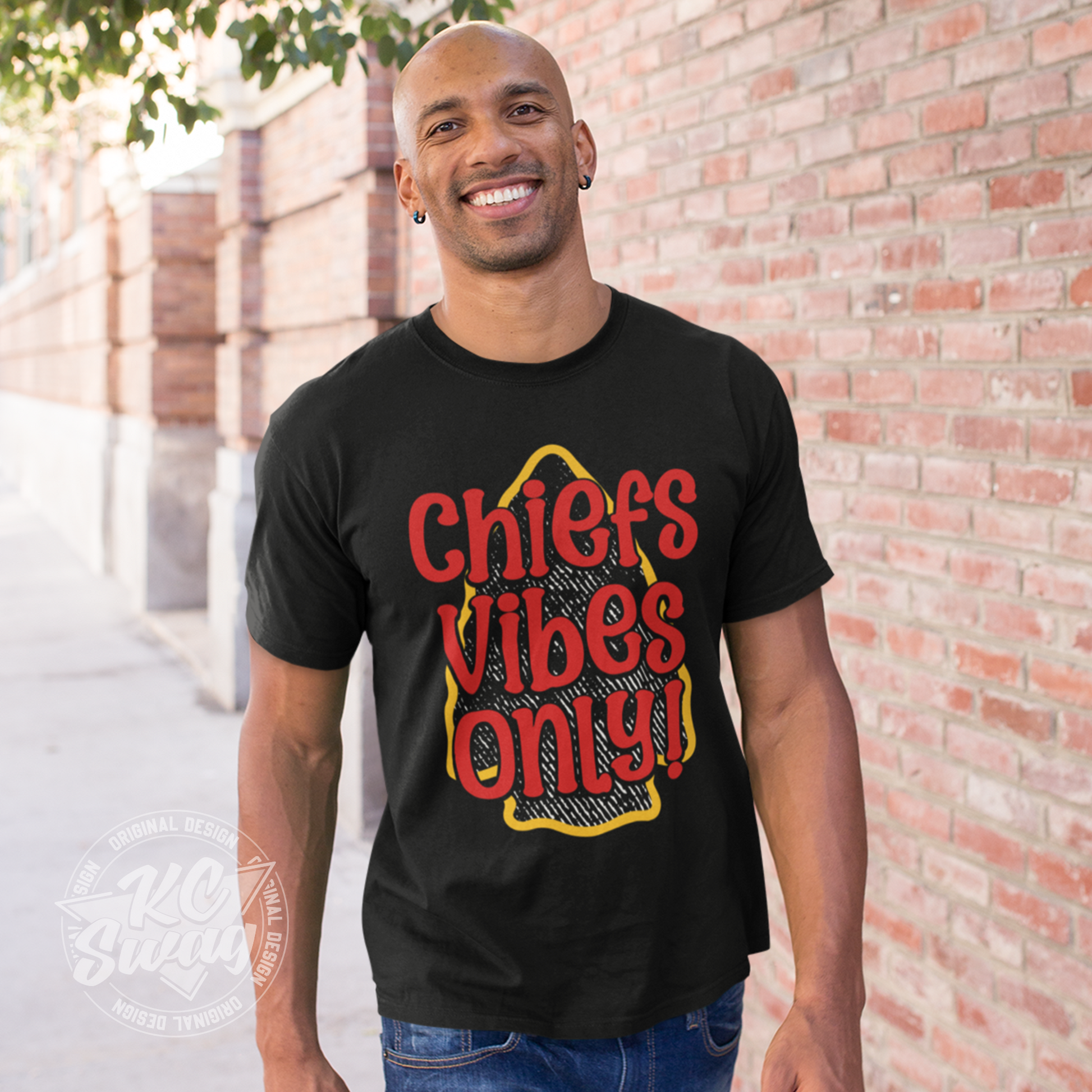 KC Swag - Kansas City Chiefs CHIEFS VIBES ONLY! on black unisex t-shirt worn by male model walking on sidewalk next to brick wall