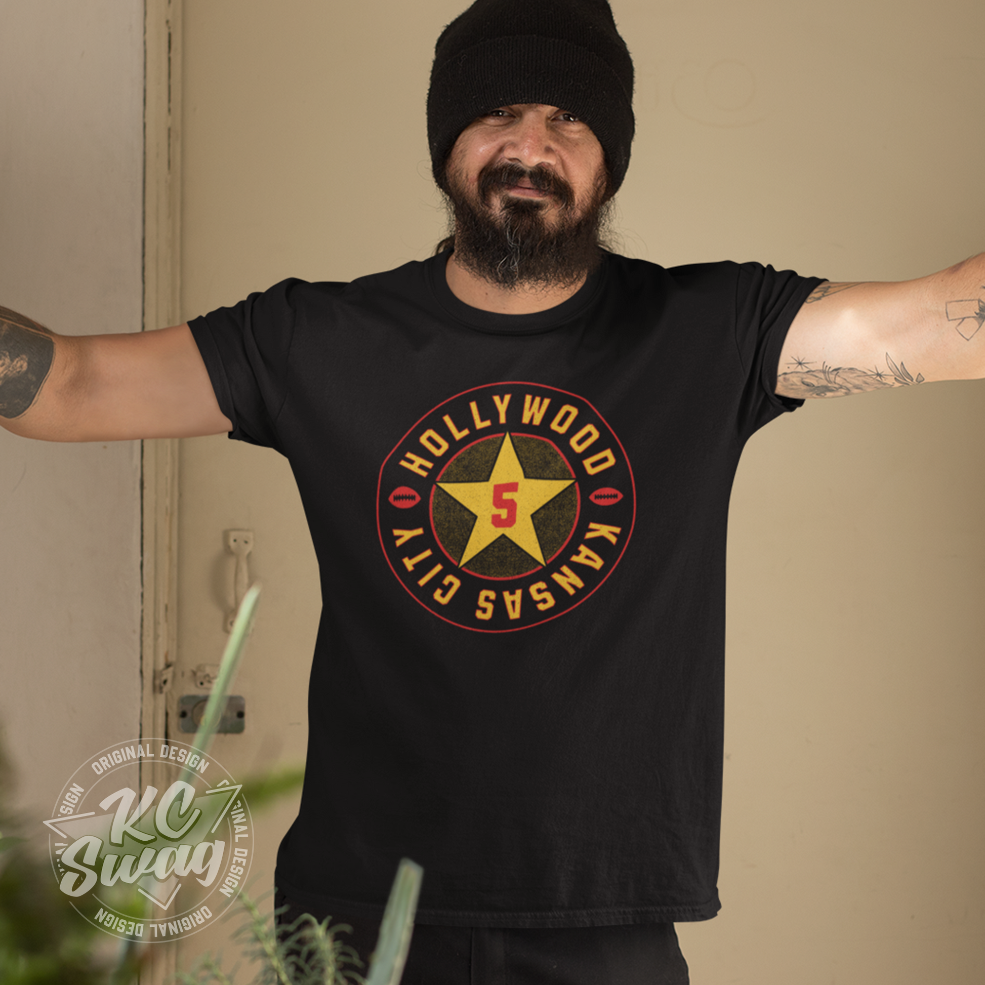 KC Swag - Kansas City Chiefs HOLLYWOOD BROWN STAR on black unisex t-shirt worn by male model standing in front of a beige door in an apartment