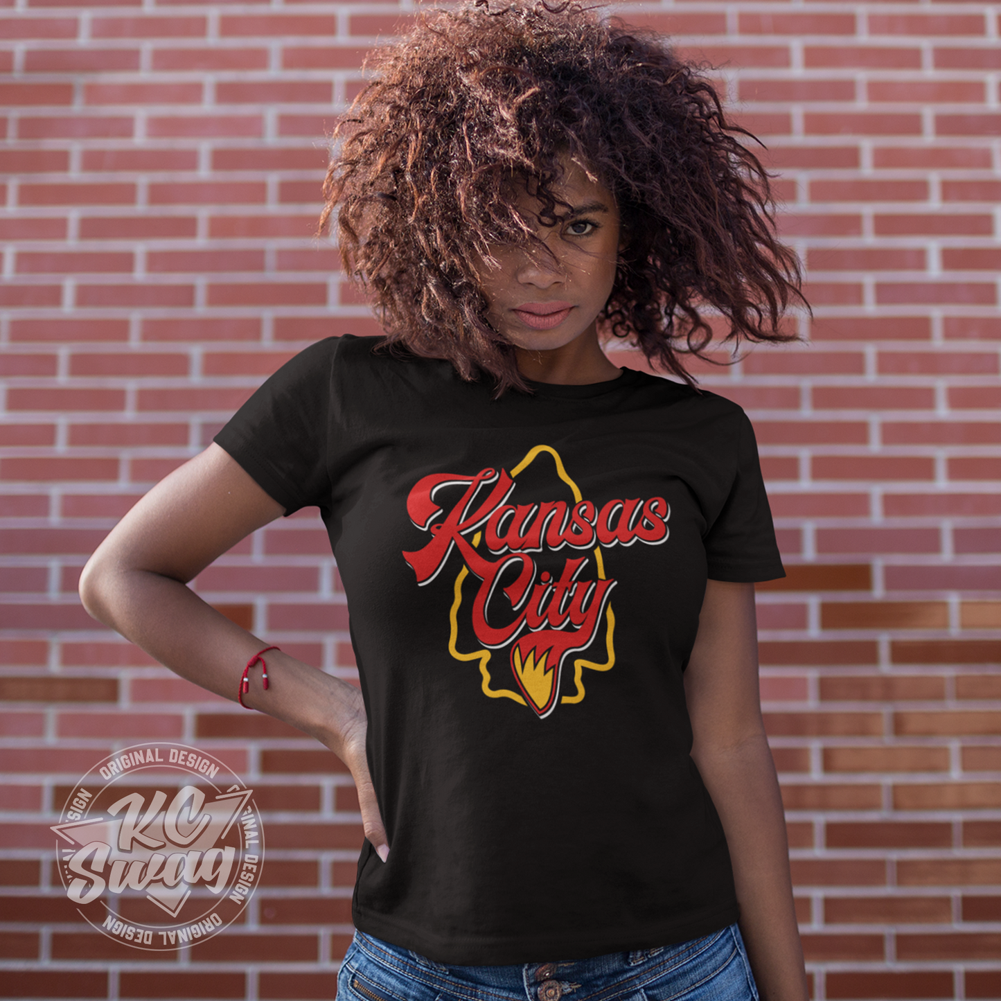 KC Swag - Kansas City Chiefs KANSAS CITY WOLF TAIL ARROWHEAD on black unisex t-shirt worn by female model standing in front of a brick wall