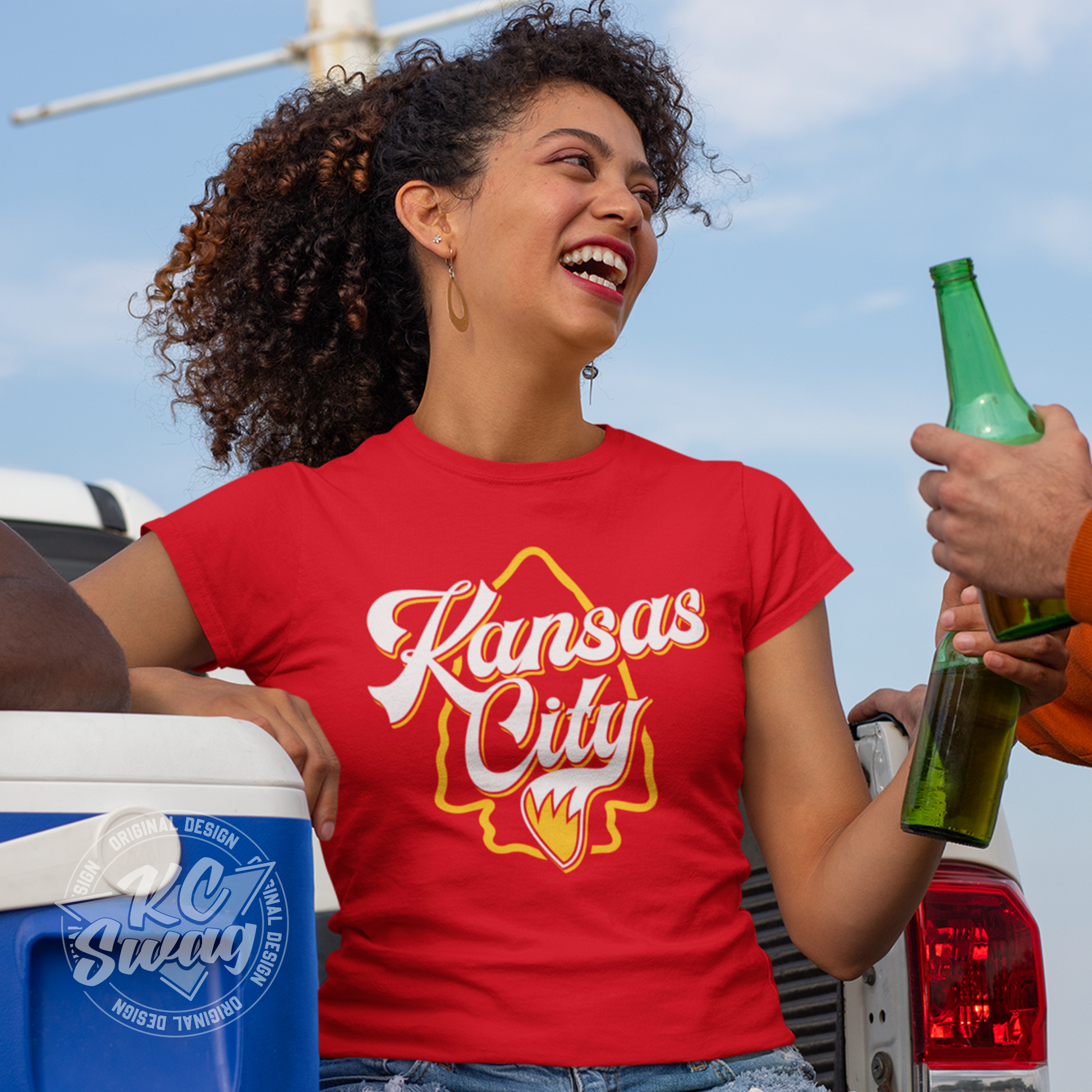 KC Swag - Kansas City Chiefs KANSAS CITY WOLF TAIL ARROWHEAD on red unisex t-shirt worn by female model sitting in the bed of a truck in a stadium parking lot