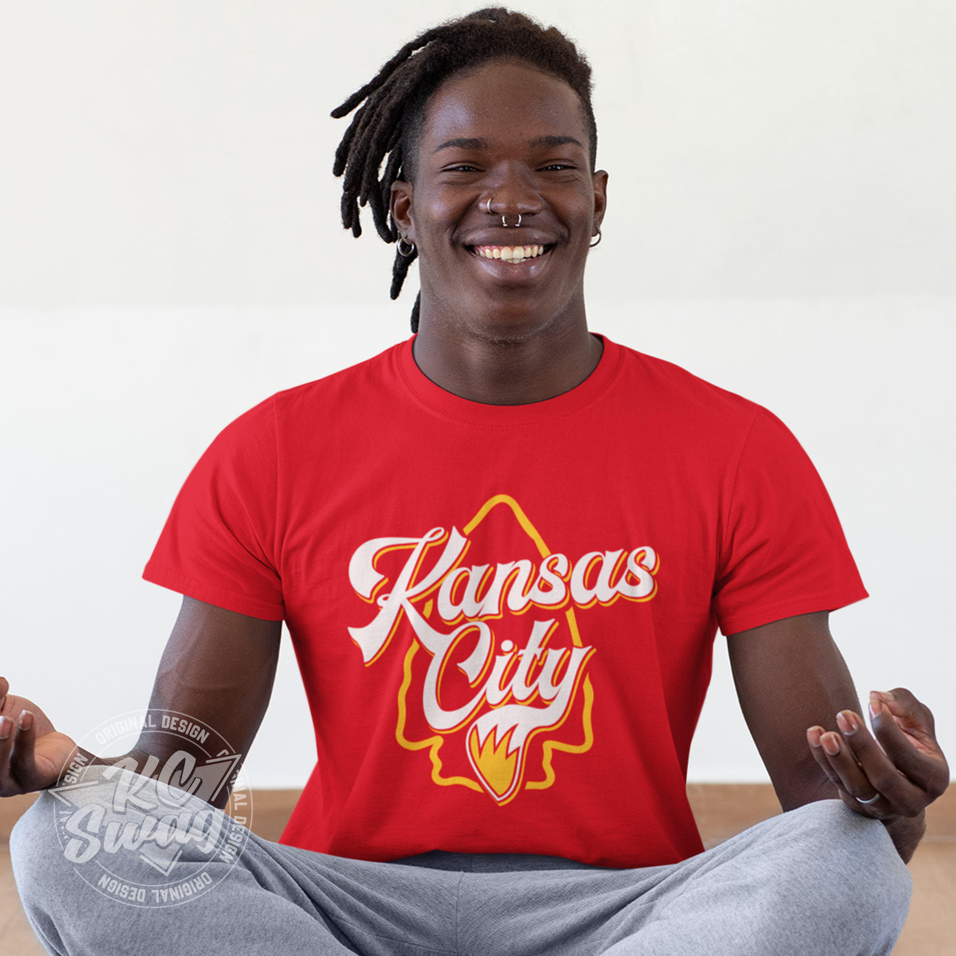 KC Swag - Kansas City Chiefs KANSAS CITY WOLF TAIL ARROWHEAD on red unisex t-shirt worn by male model sitting crossed-legged in a yoga studio