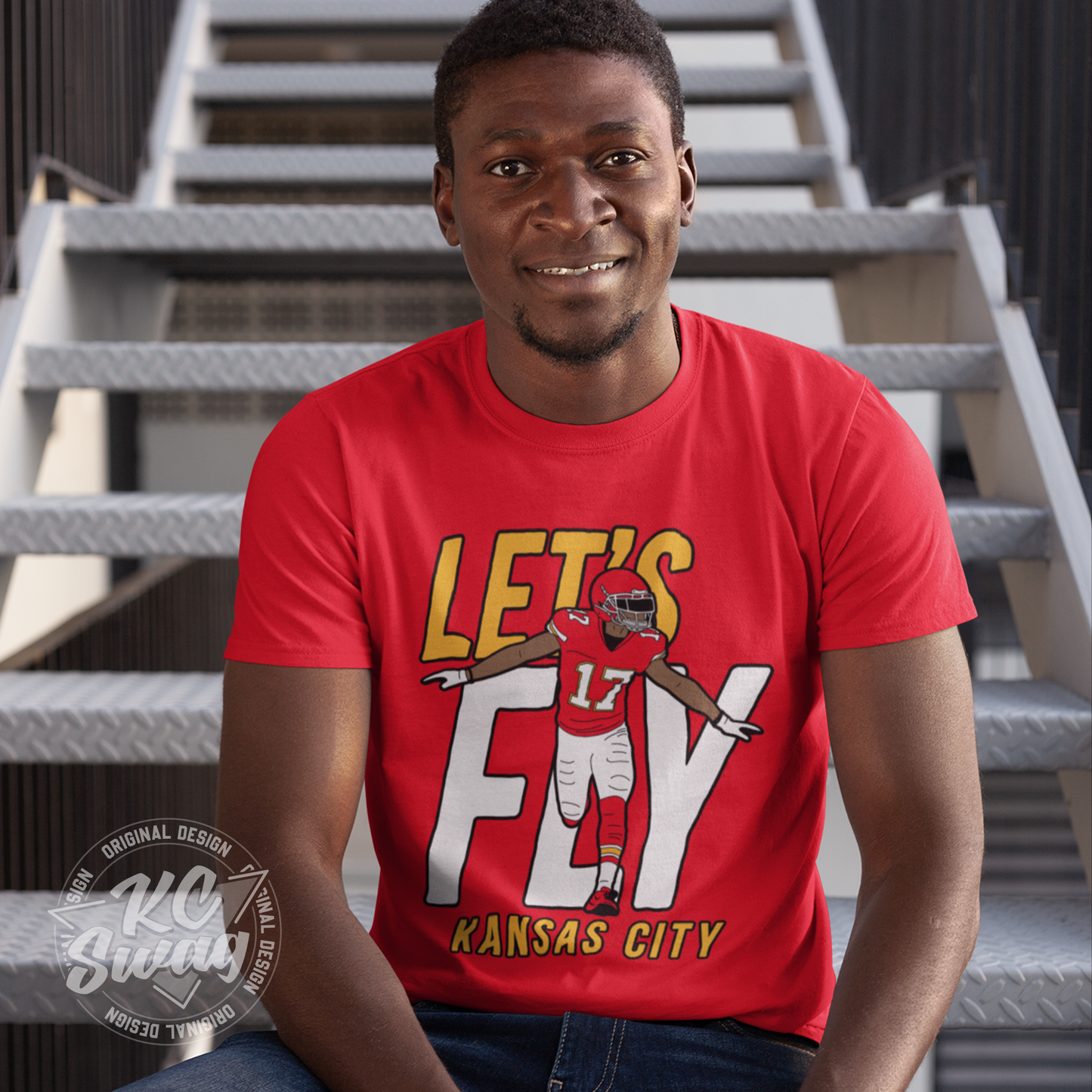 KC Swag - Kansas City Chiefs LET'S FLY HARDMAN KANSAS CITY on red unisex t-shirt worn by male model sitting on metal stairs