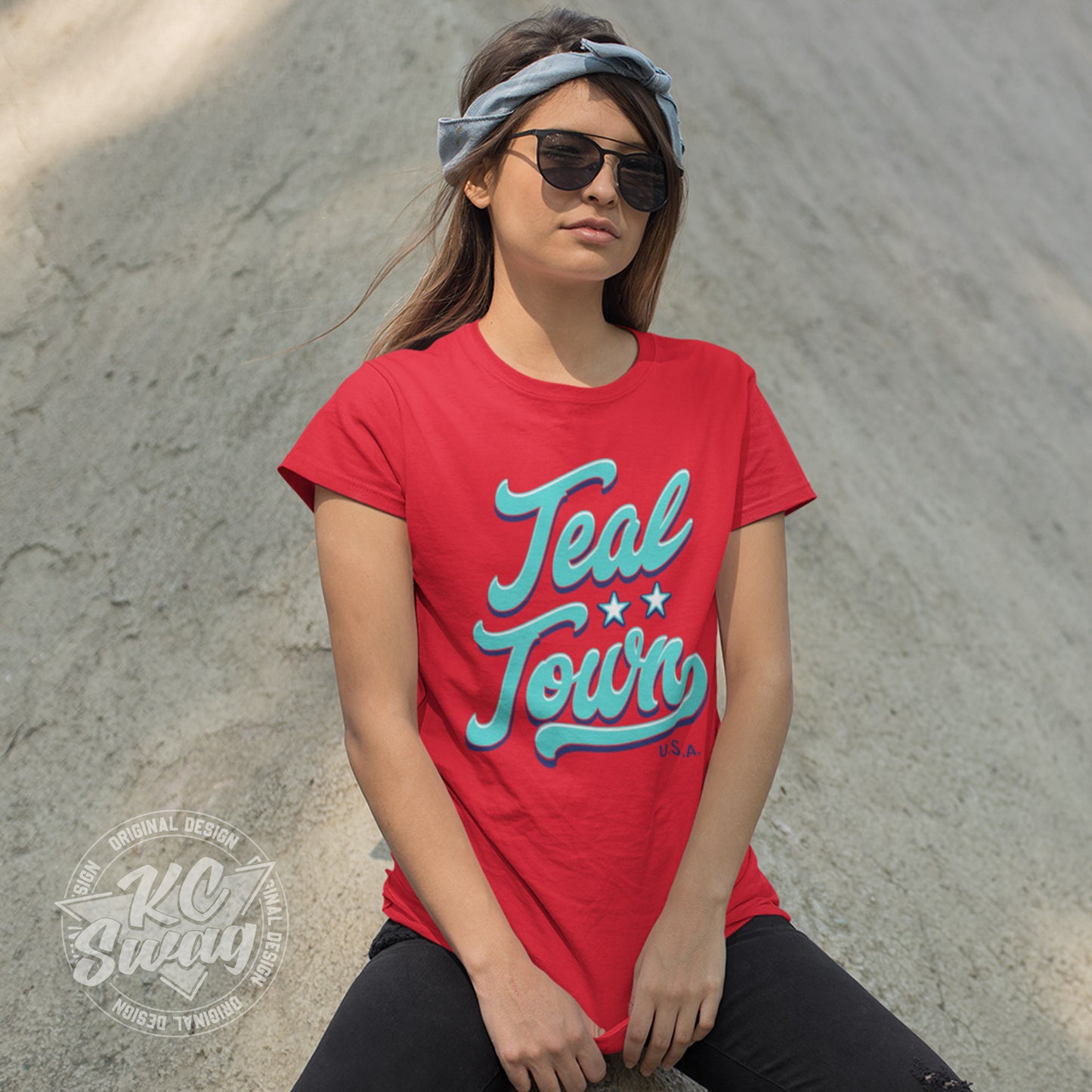 KC Swag - Kansas City Current, Teal Town USA design on red unisex t-shirt worn by sunglasses and bandana sporting female model leaning on concrete wall