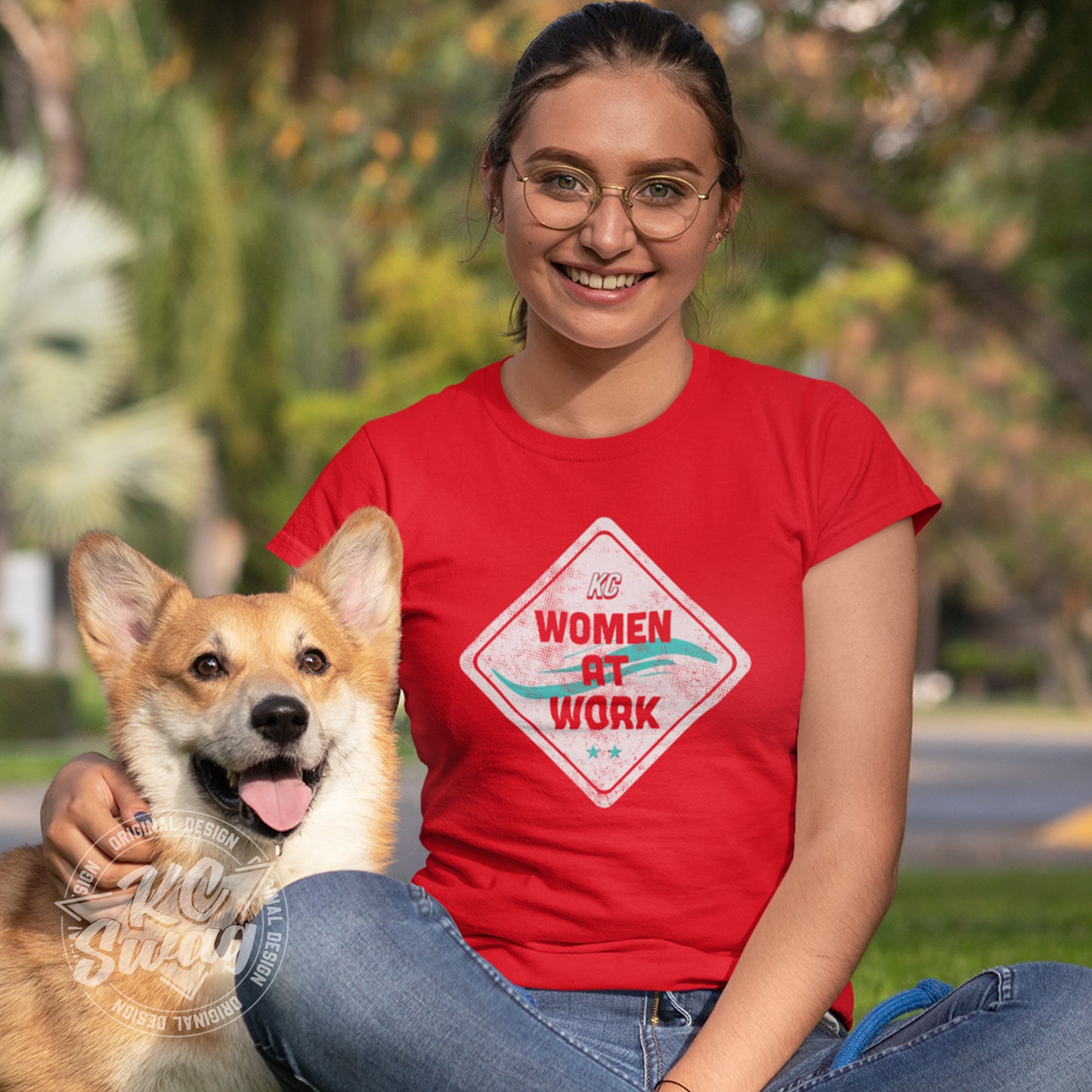  worn by female model sitting on the grass in a park with her corgi dog