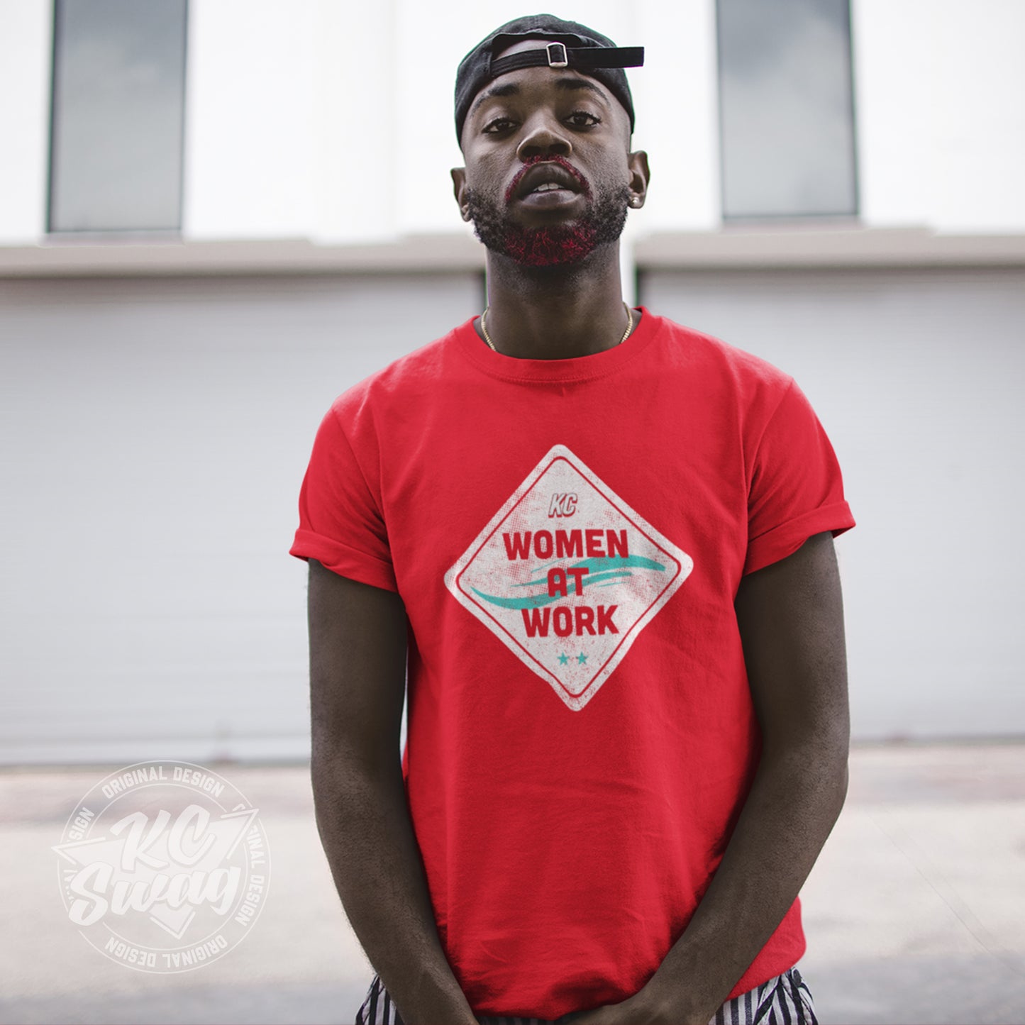 KC Swag - Kansas City Current, Women At Work Construction Sign design on a red unisex t-shirt worn by male model standing in an urban alley wearing a backwards ball cap