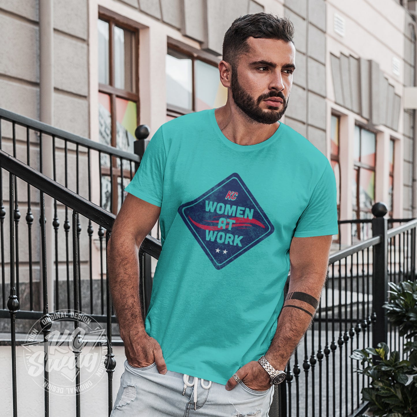 KC Swag - Kansas City Current, Women At Work Construction Sign design on a teal unisex t-shirt worn by male model leaning on rot iron fence in front of townhouse