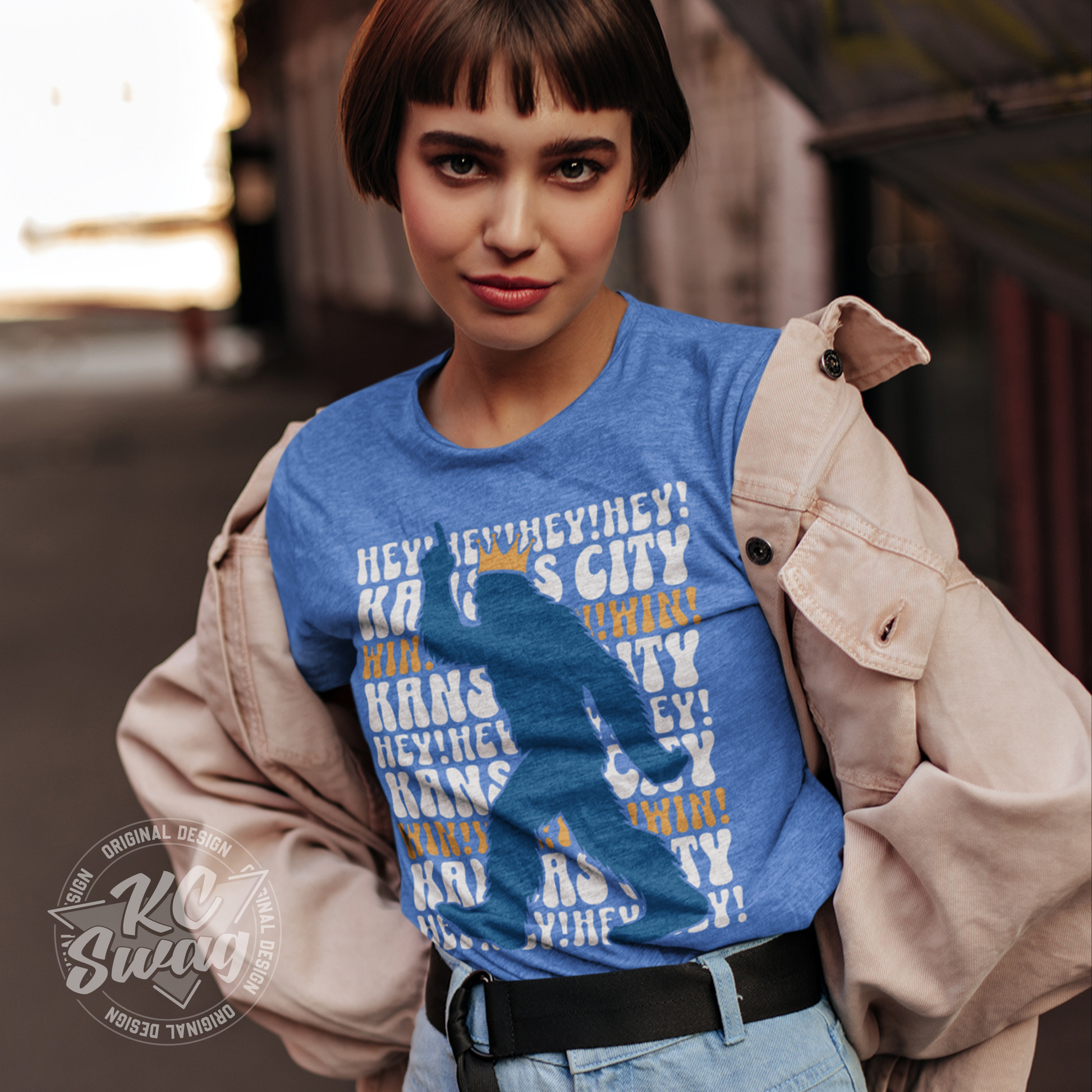 KC Swag - Kansas City Royals HEY HEY HEY PASQUATCH on a true heather columbia blue unisex t-shirt won by female model under an open jacket in front of a old barn