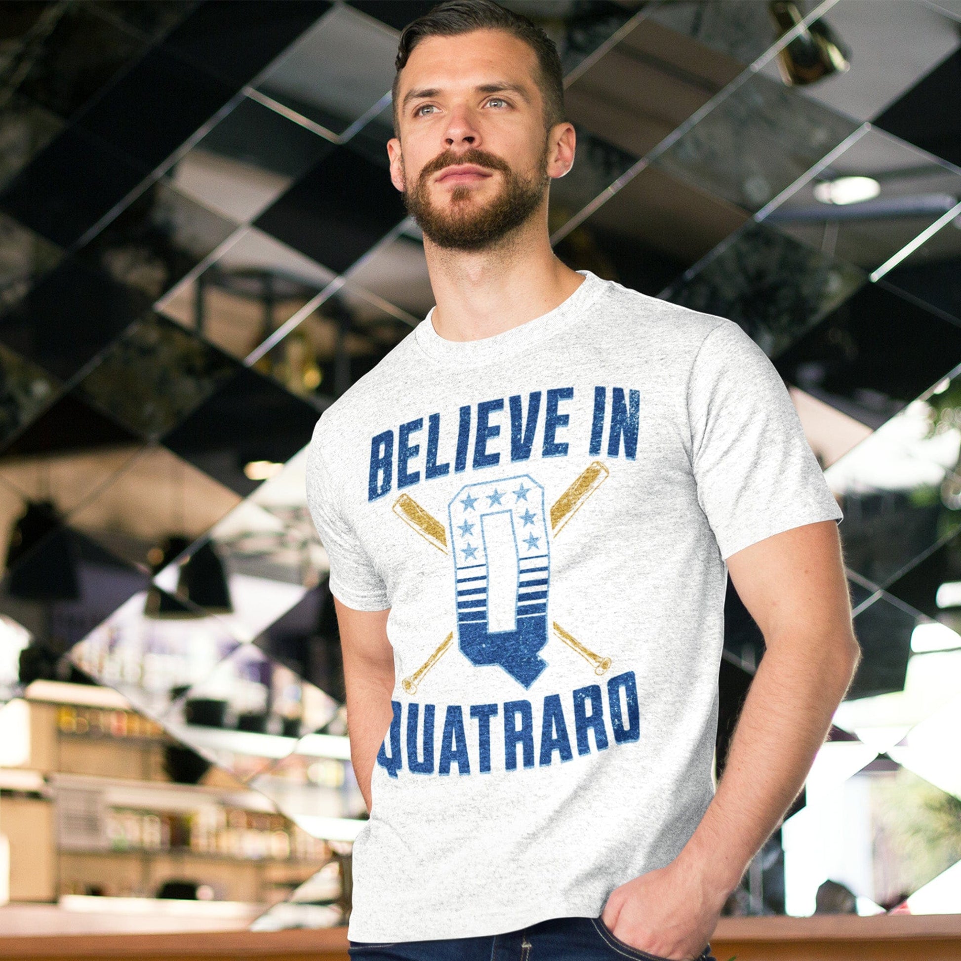KC Swag Kansas City Royals royal blue, powder, gold, white BELIEVE IN Q on ash heather grey unisex t-shirt worn by male model in front of a wall of mirrors