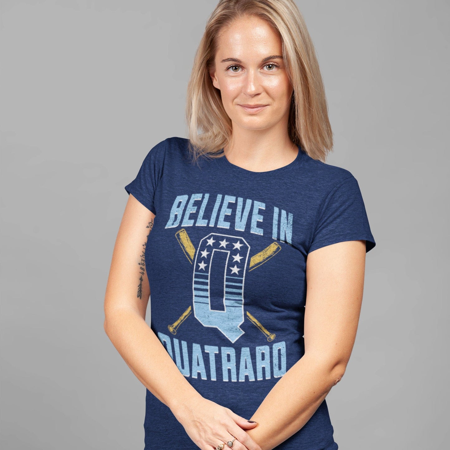 KC Swag Kansas City Royals royal blue, powder, gold, white BELIEVE IN Q on heather navy unisex t-shirt worn by female model standing in front of grey wall