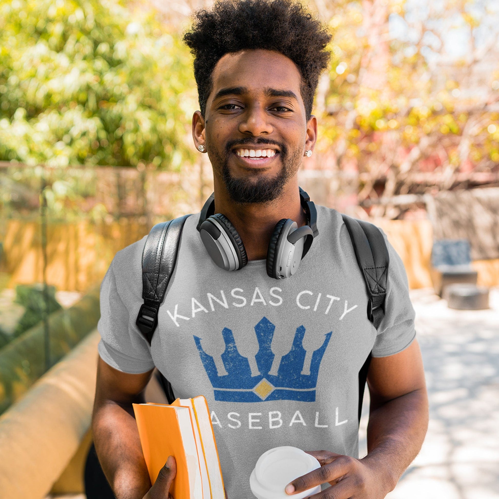 KC Swag Kansas City Royals white/blue KANSAS CITY BASEBALL BOTTLE CROWN on athletic heather grey t-shirt worn by male model wearing backpack and carrying books