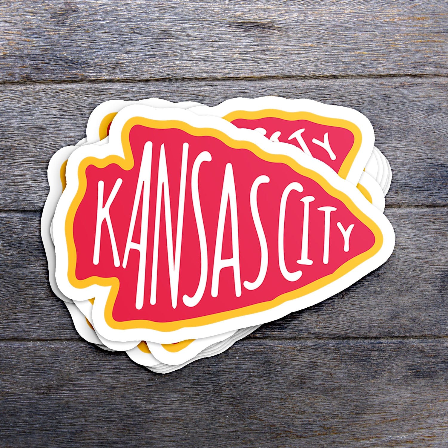 KC Swag Kansas City Chiefs red, yellow KC ARROWHEAD vinyl die cut decal sticker stack on dark wood table