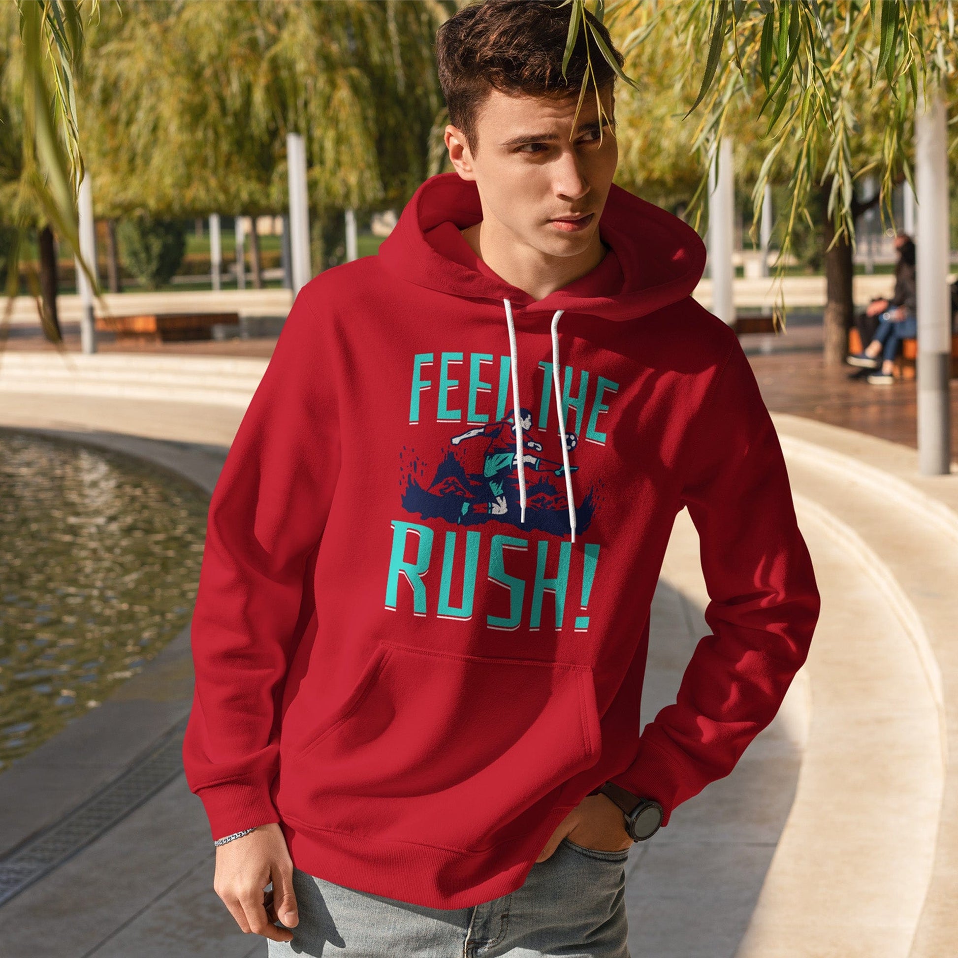 KC Swag Kansas City Current FEEL THE RUSH on red fleece pullover hoodie worn by male model near water in a public park