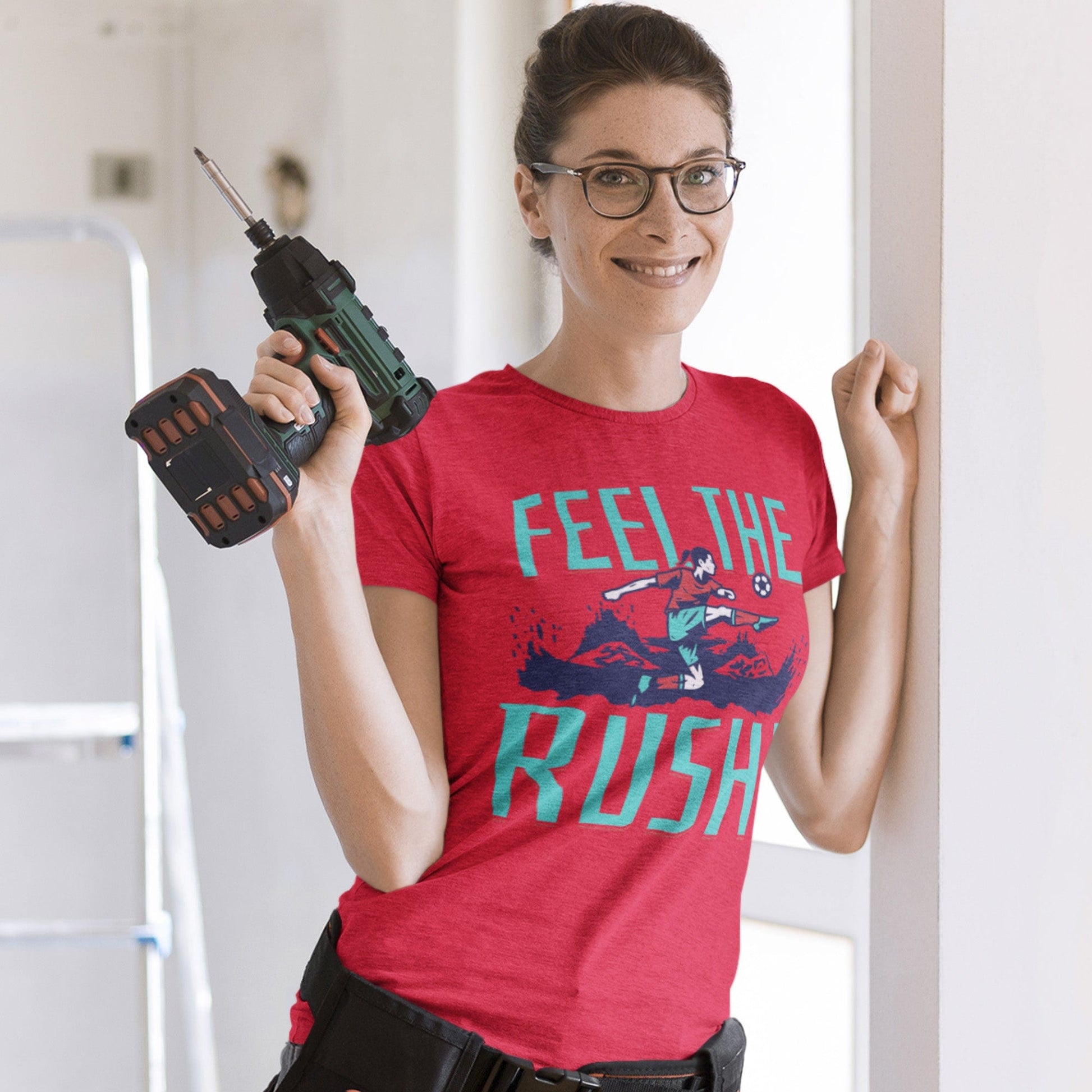 KC Swag Kansas City Current FEEL THE RUSH on heather red unisex t-shirt worn by female model holding a power drill in a remodeling zone
