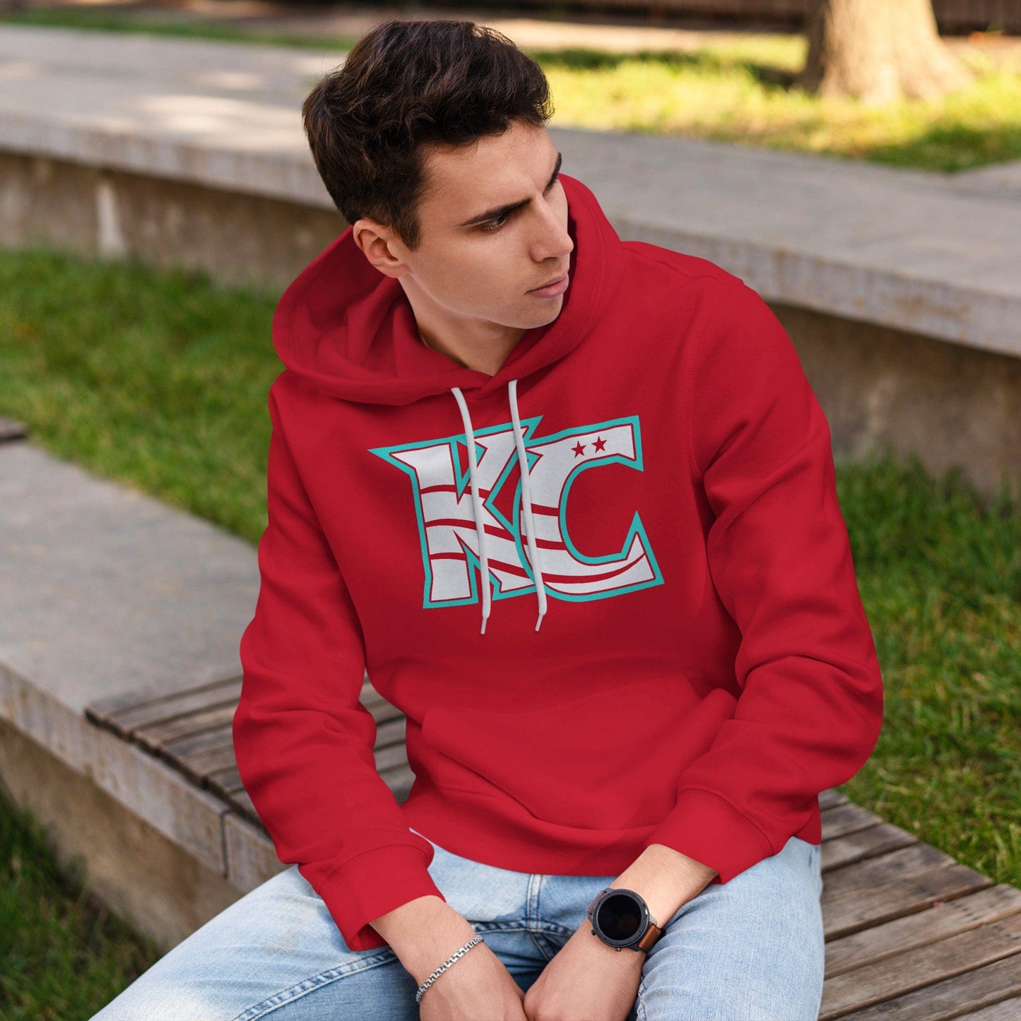 KC Swag Kansas City Current CURRENT KC on red fleece pullover hoodie worn by male model sitting on bench in public parl